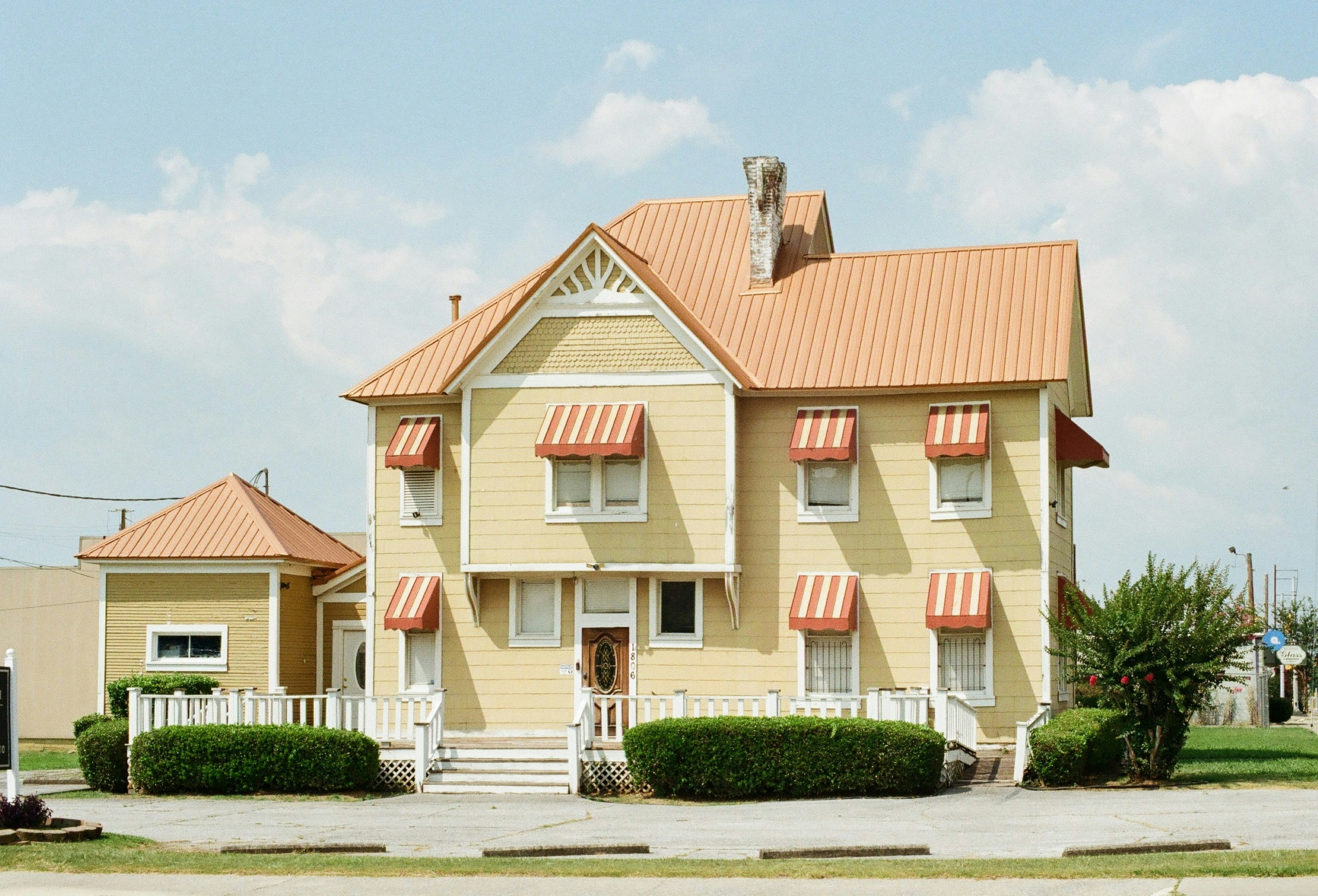 A yellow house with an orange roof and striped awnings.