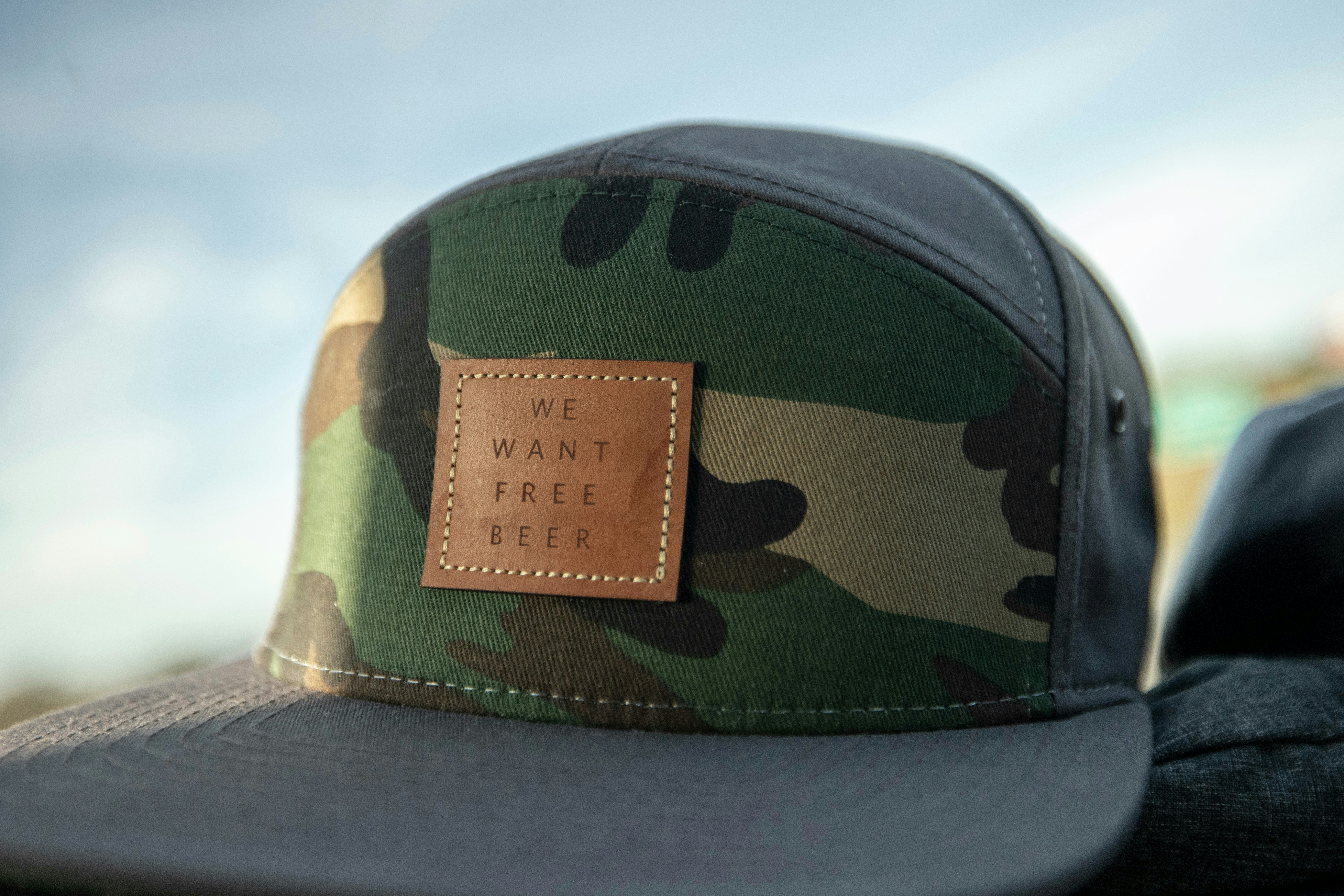A camouflage baseball cap with a brown leather patch.