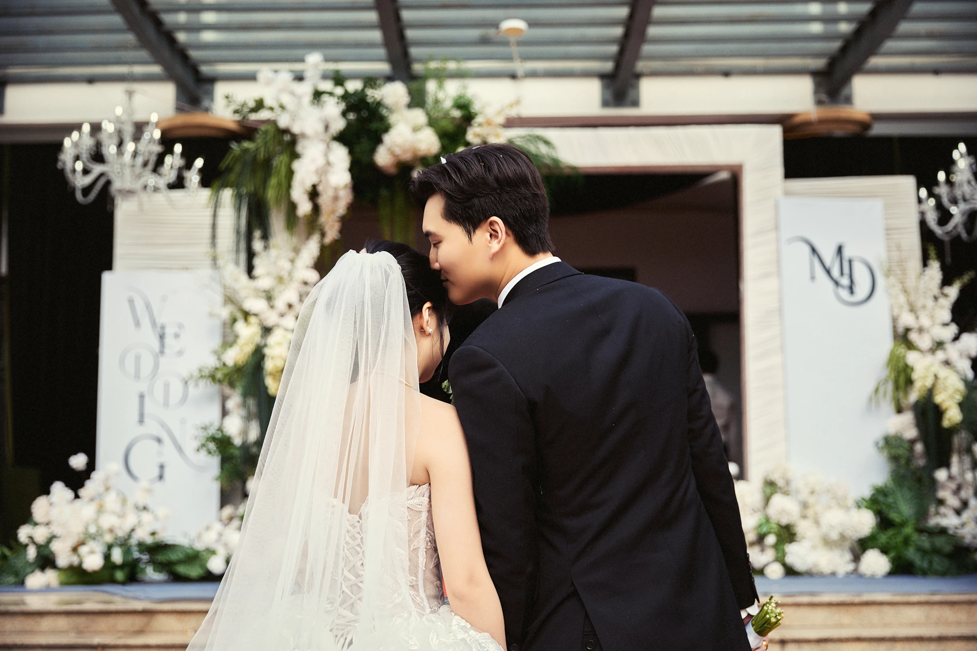 Groom kisses bride's forehead during their wedding celebration.