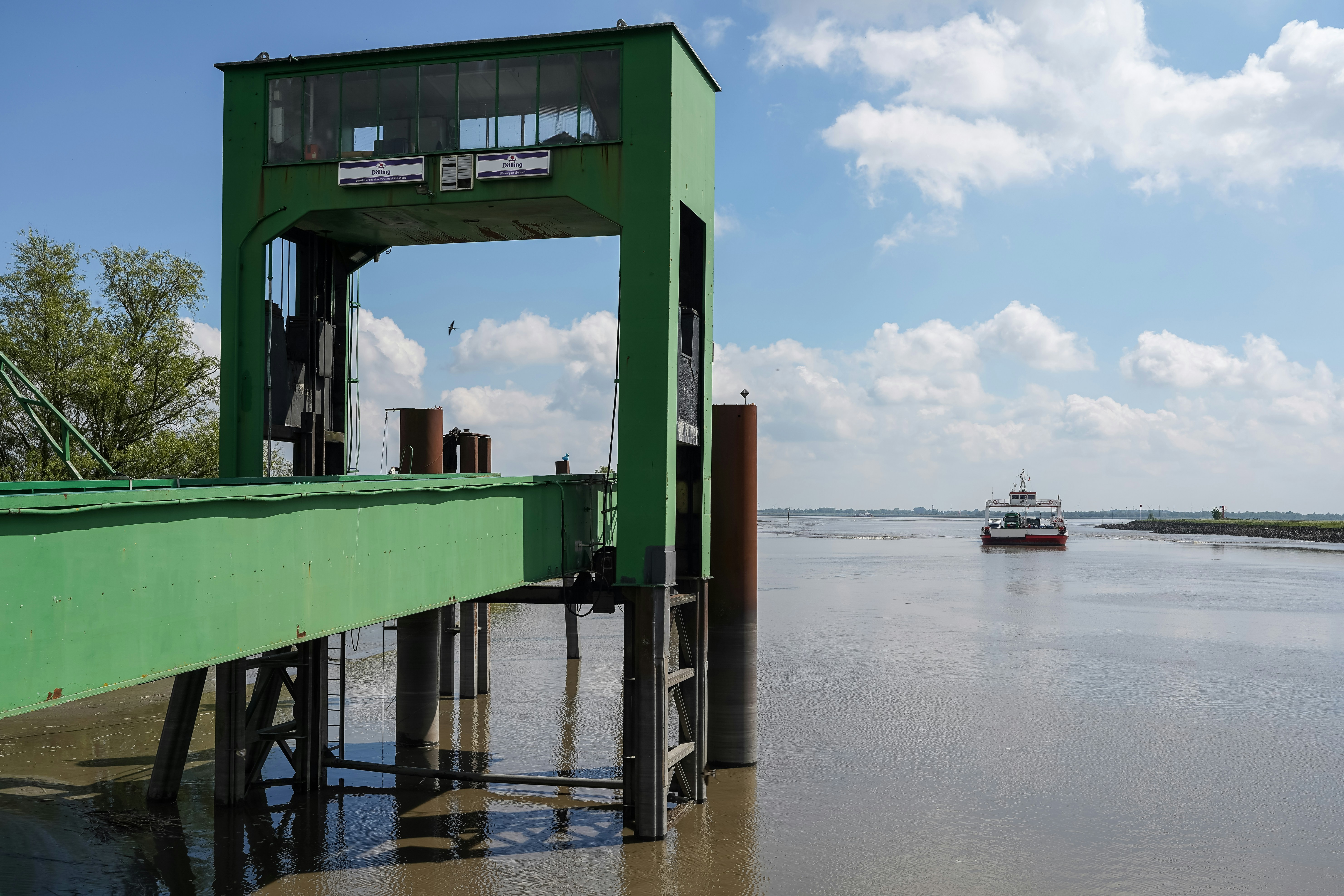 Green pier and a boat on a wide river.