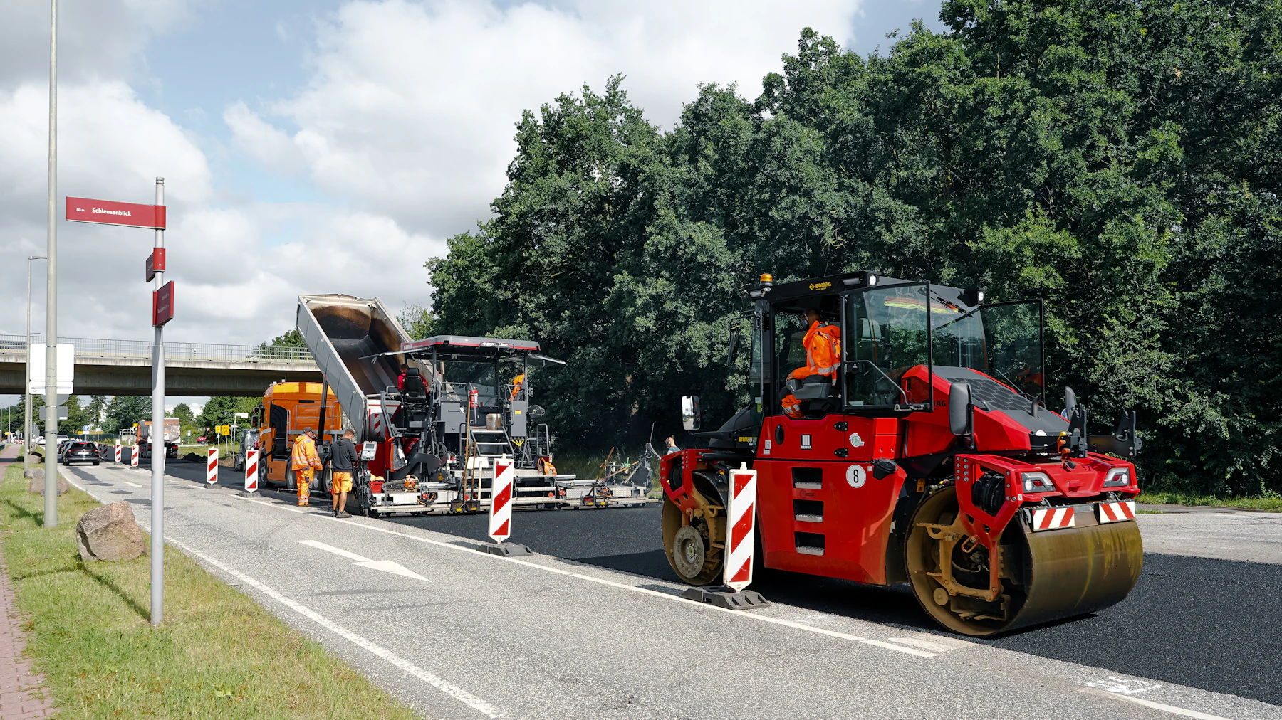 Red roller and asphalt paver working together on new pavement