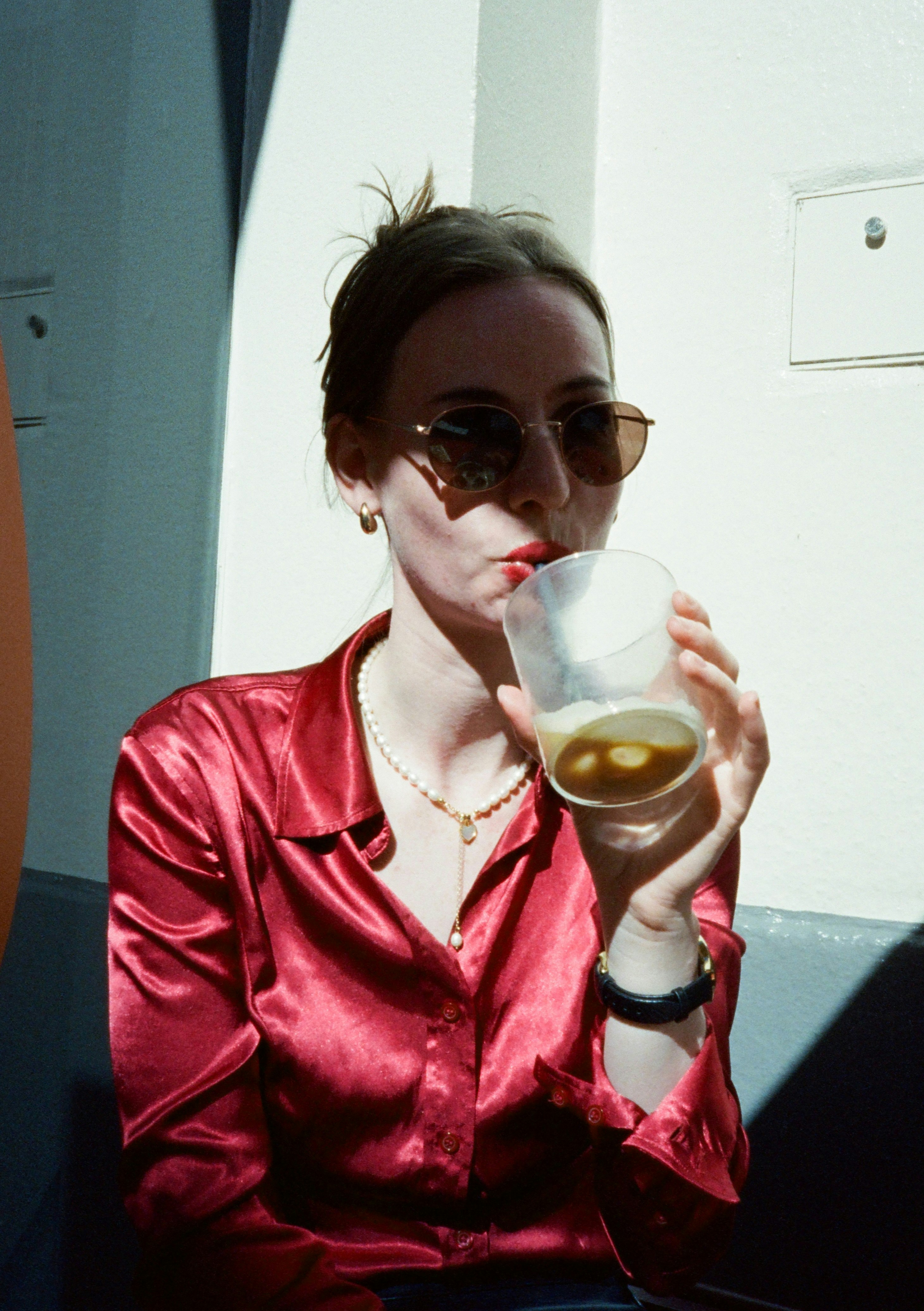 A woman wearing sunglasses sips a drink
