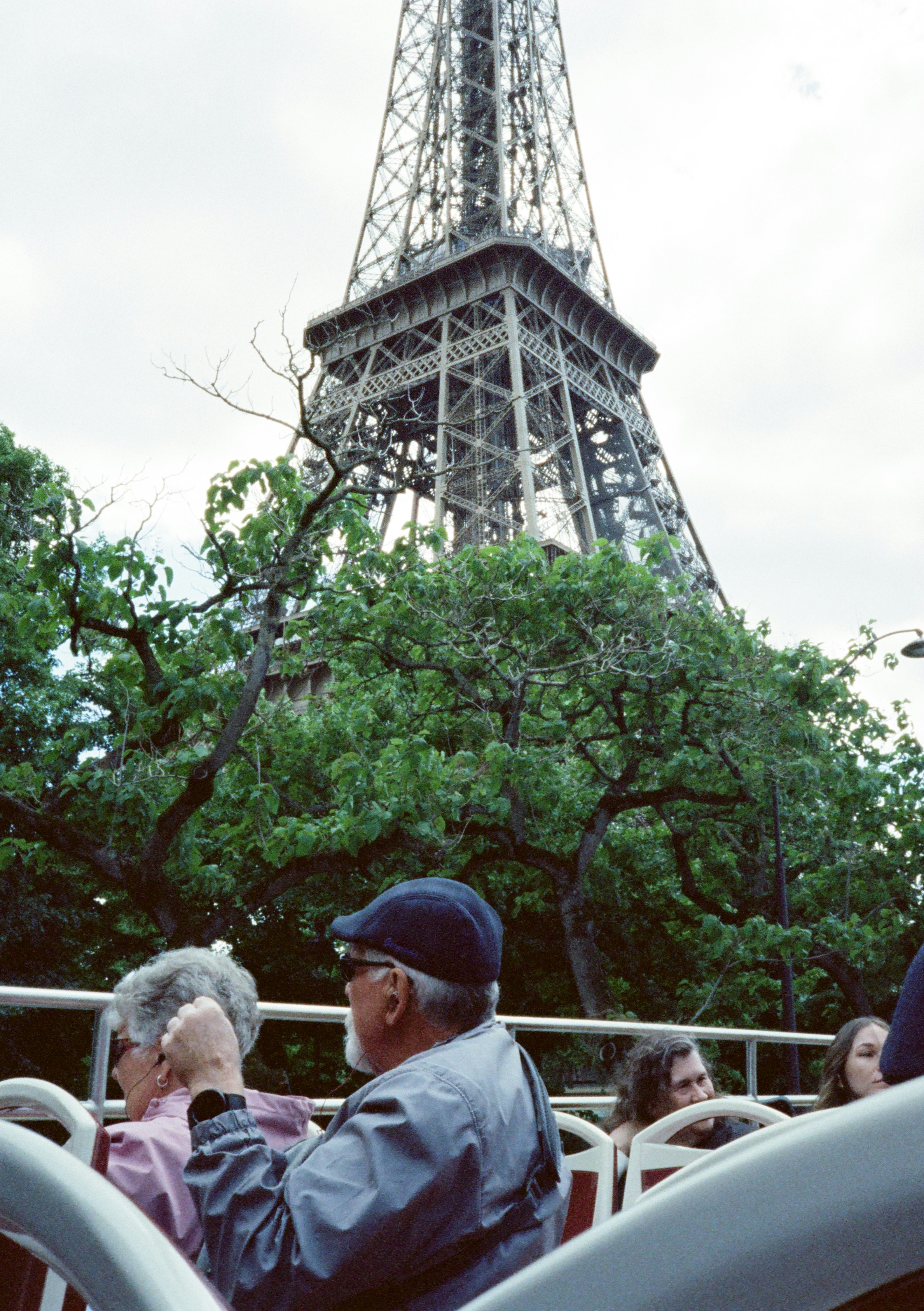 Tourists on a bus view the eiffel tower through trees