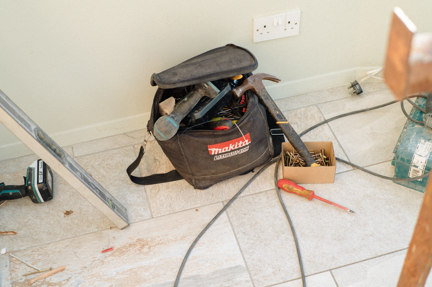 Repair tools screws and hardware arranged beside a tool bag for a home improvement project