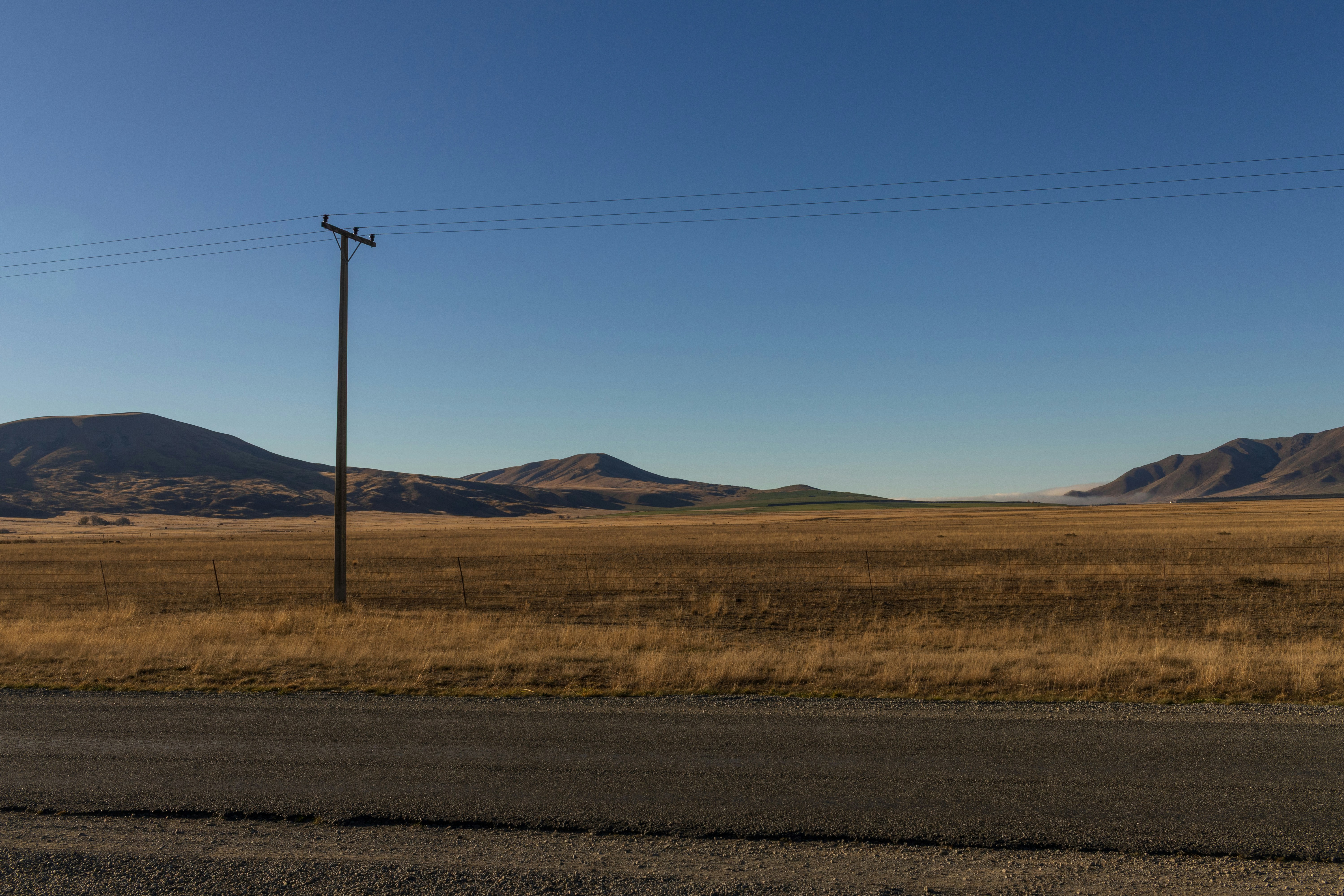 Dry golden field with a utility pole and distant mountains.
