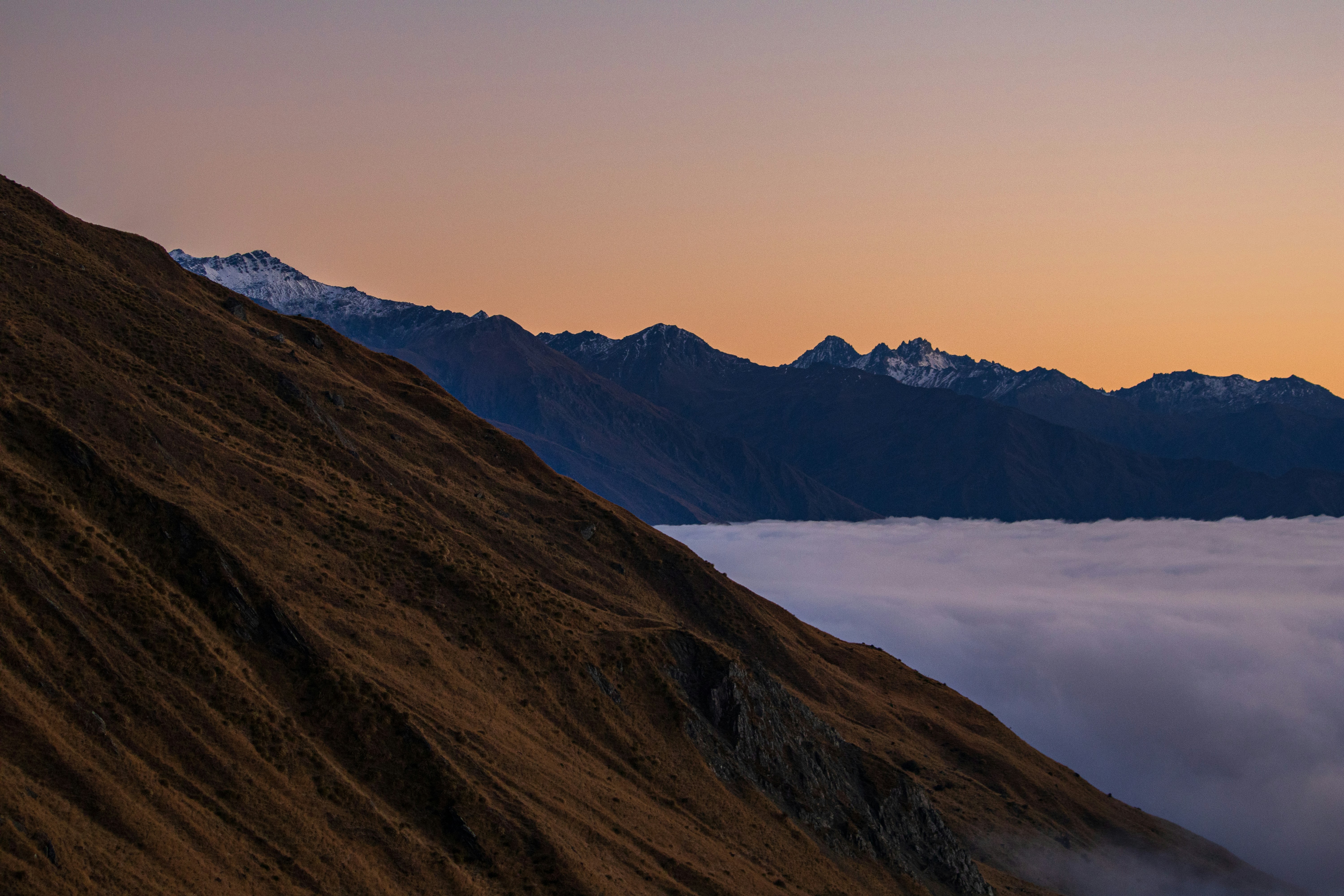 Sunrise over mountain peaks, clouds filling the valley.