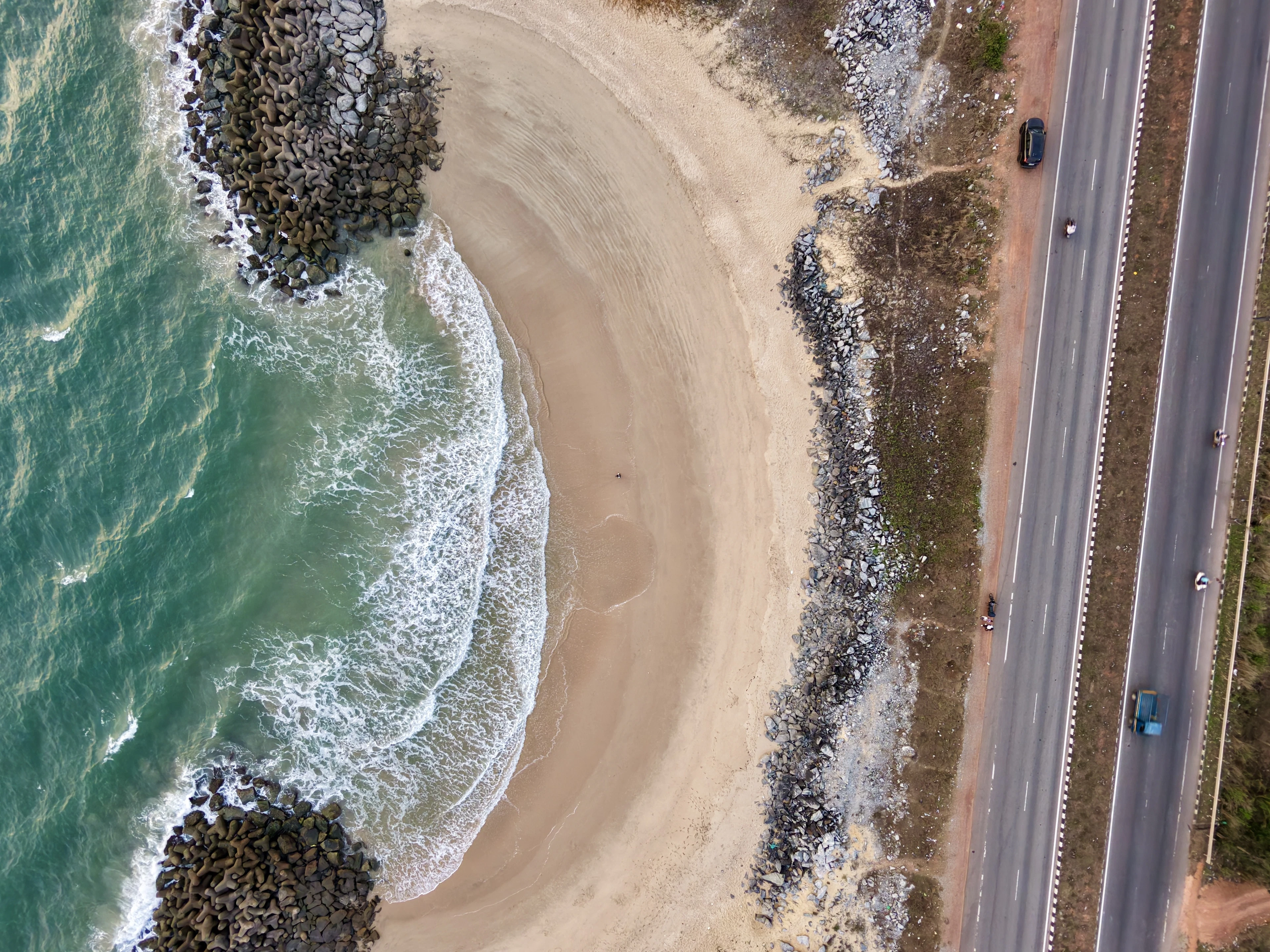 Aerial coastal road curving beside a turquoise beach