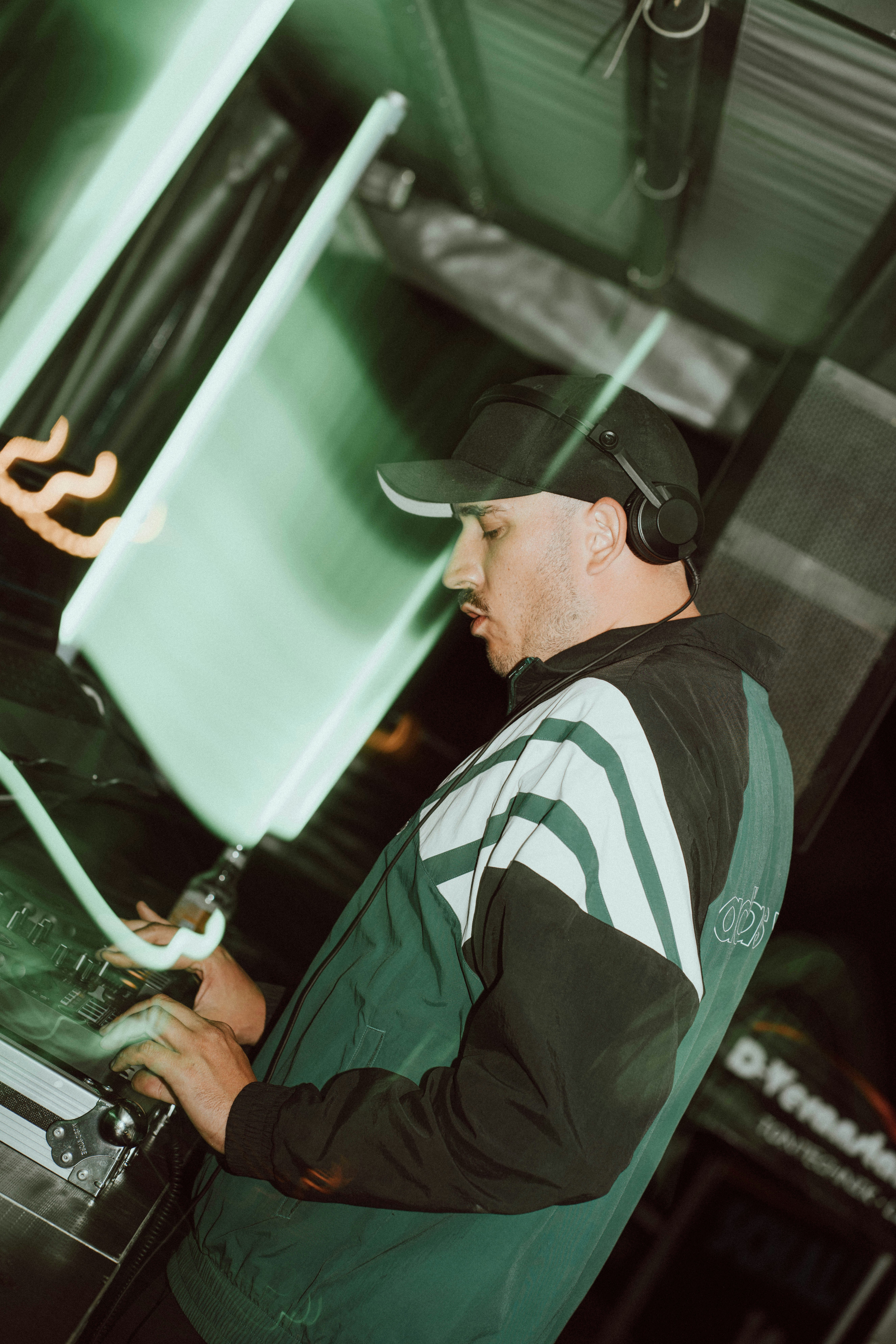Dj with headphones operating equipment, green lights