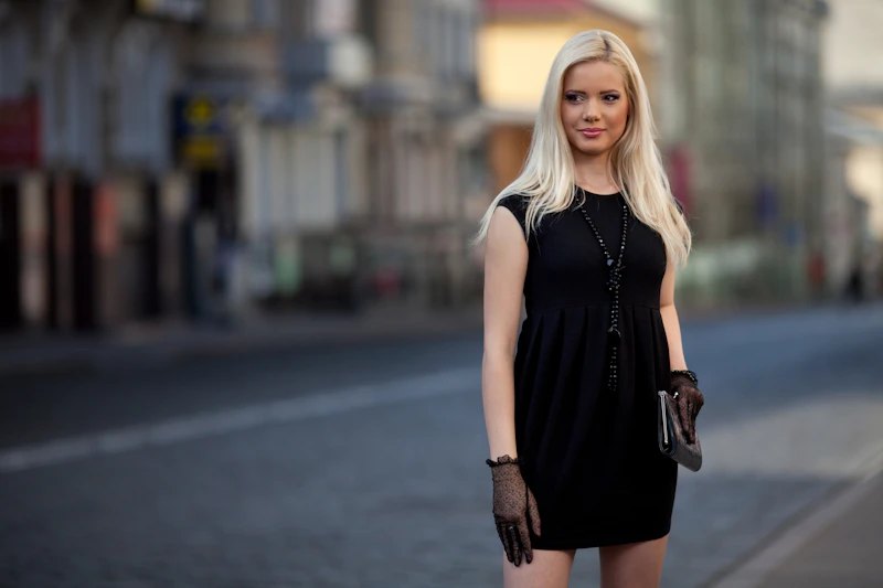 blonde woman in black dress on city street