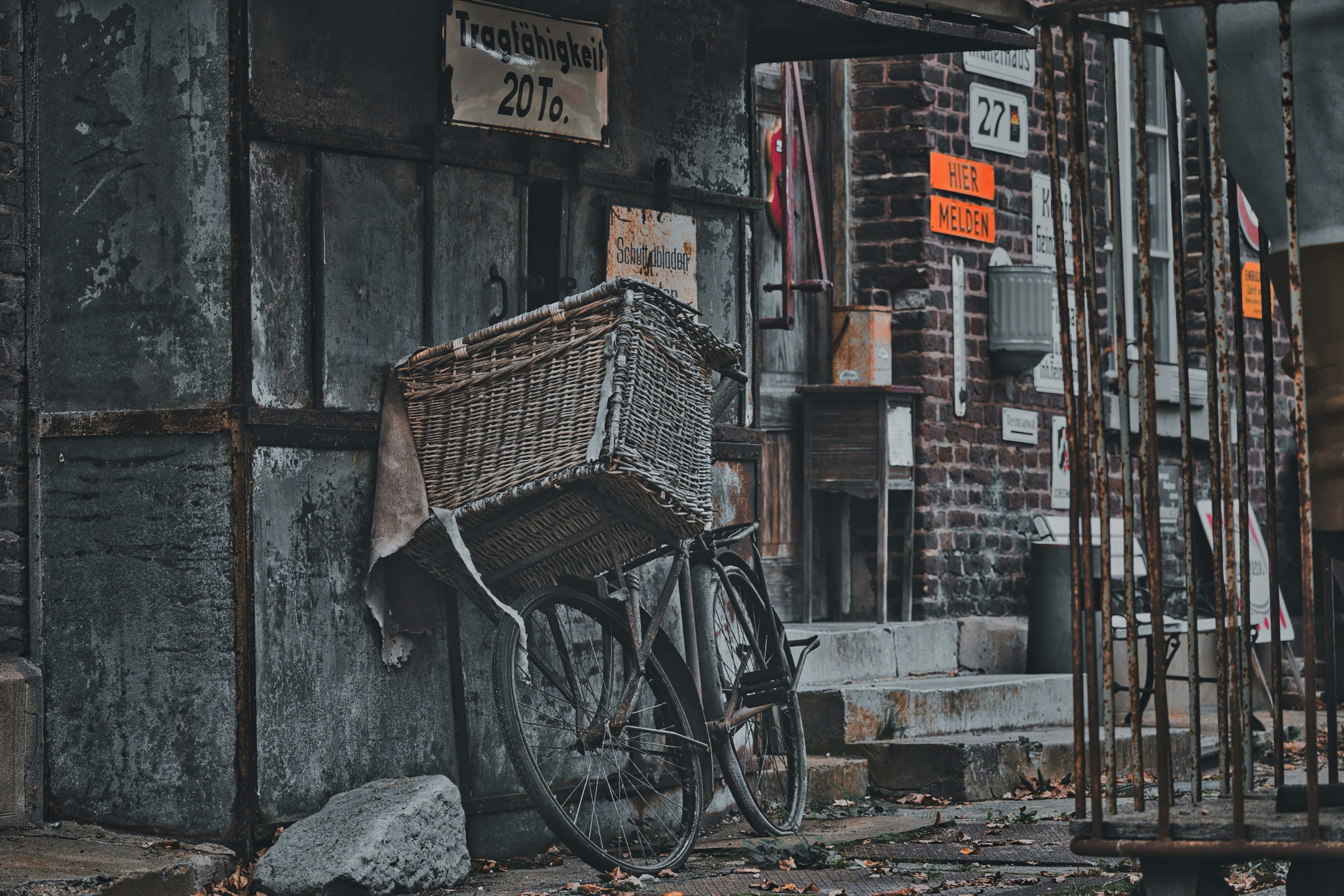 Vintage bicycle with wicker basket parked against an old building.