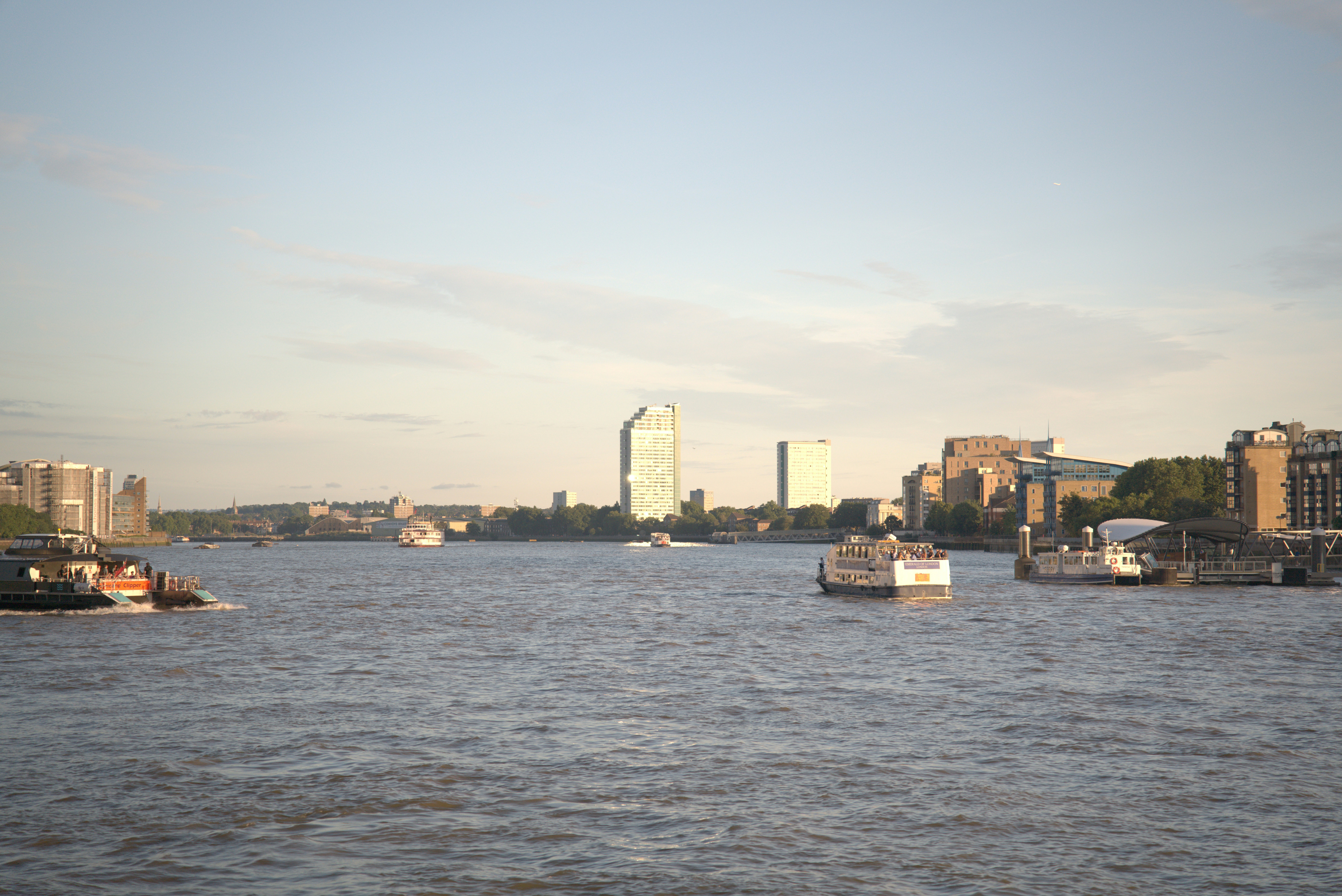 Boats on a wide river with a city skyline.