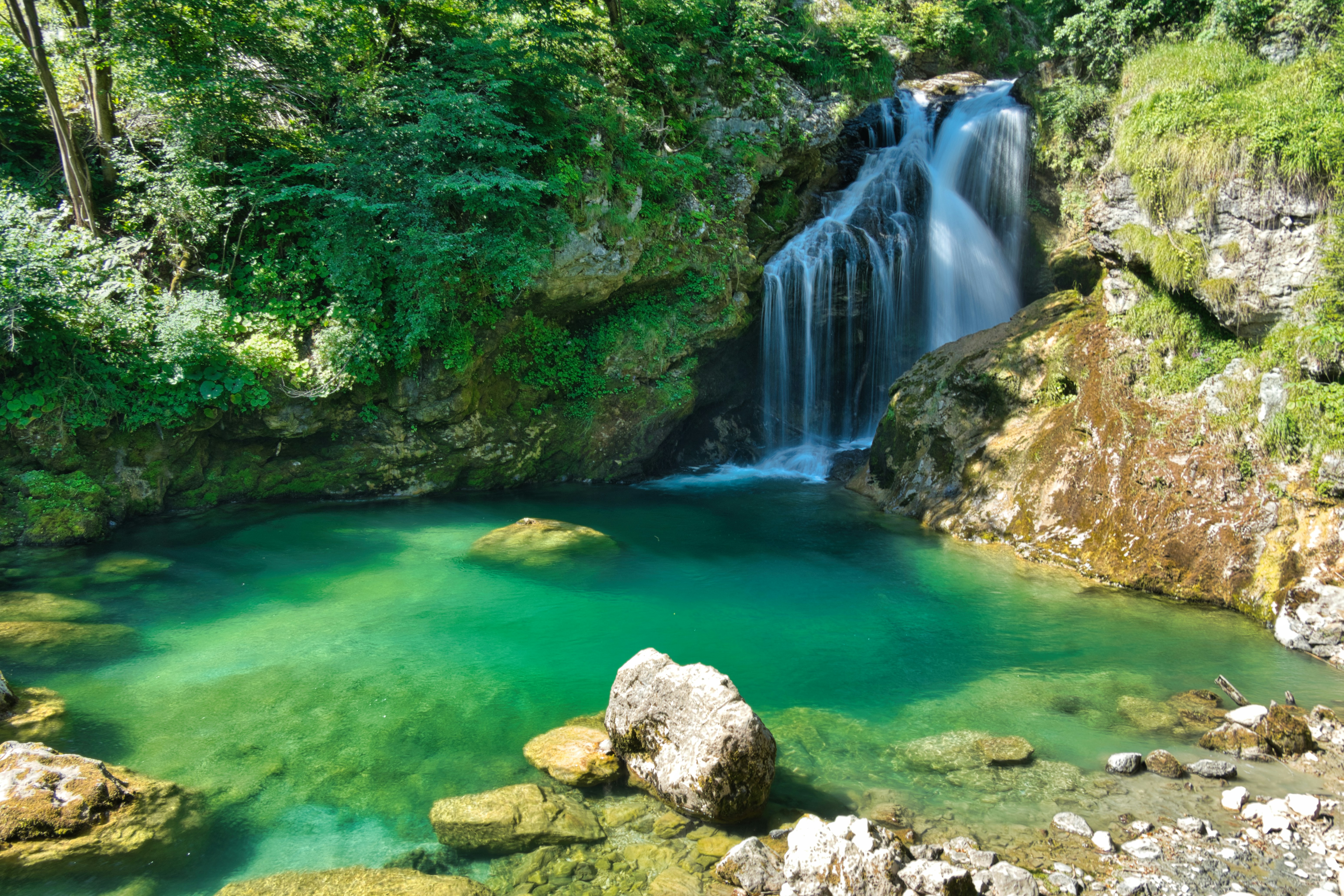 Singsing Waterfall — Placid natural bathing basin shaded by mature trees, ideal for a refreshing swim.