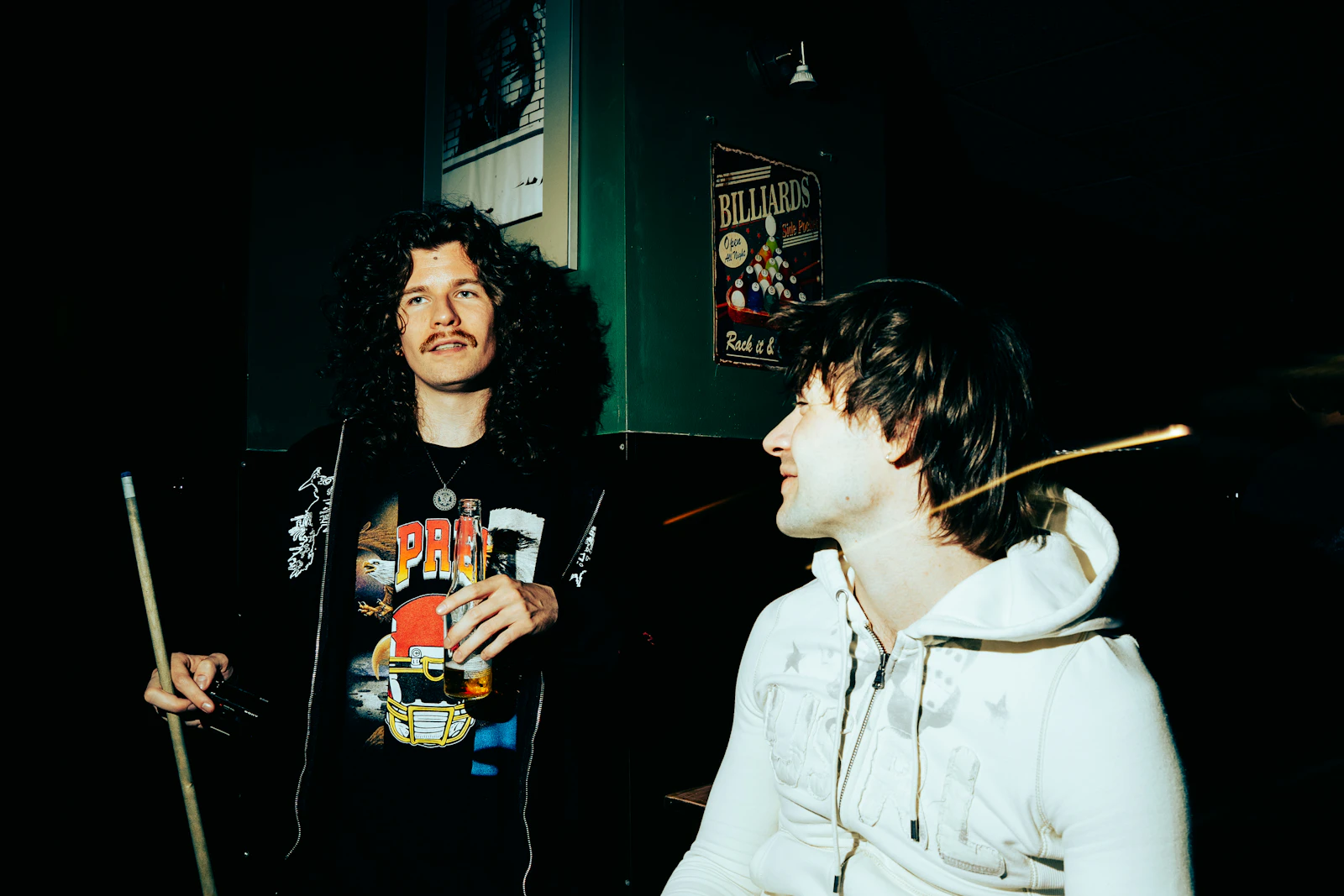 Two men playing pool at a dimly lit bar