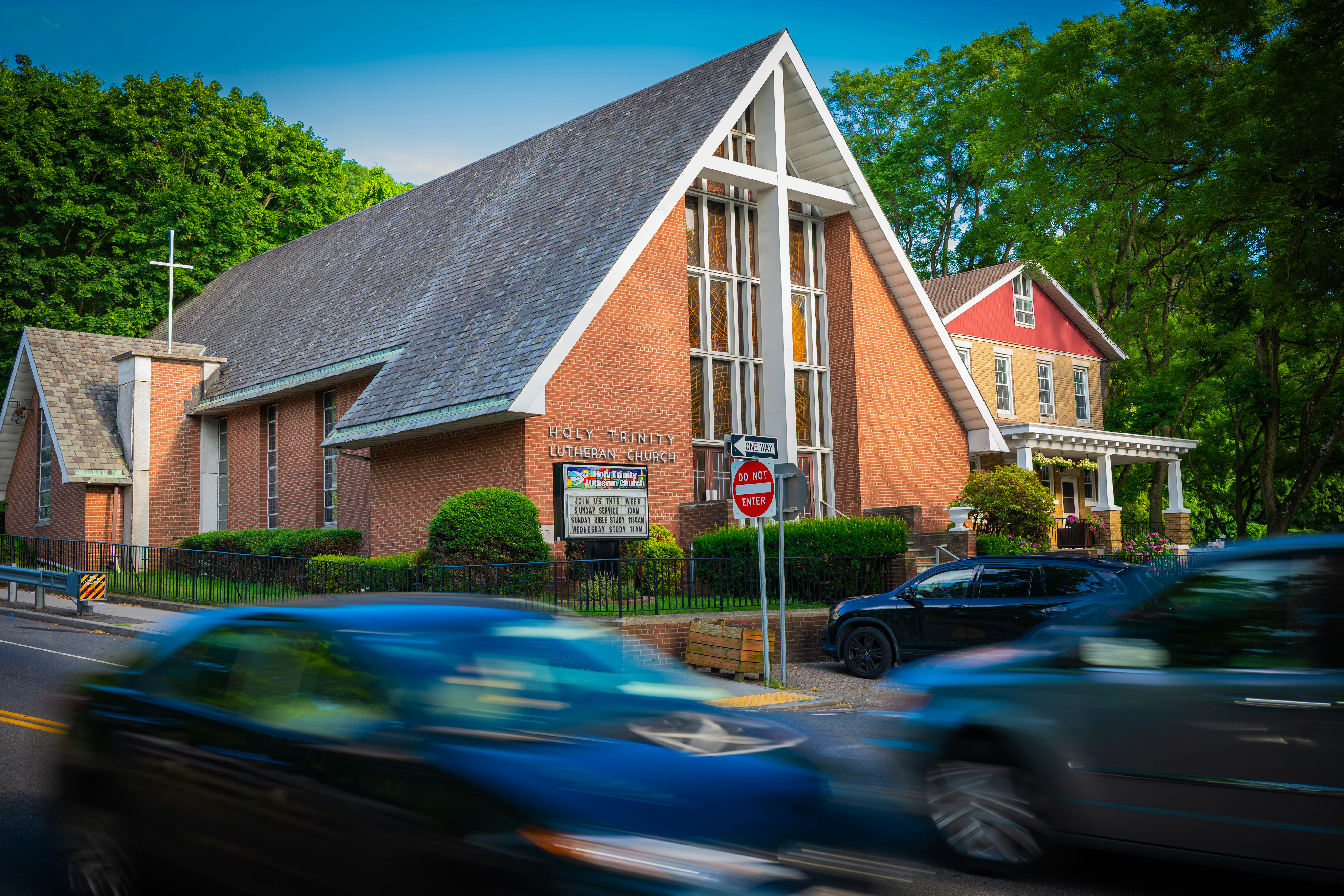 Kirche mit einem Kreuz und verschwommenen Autos auf einer Straße