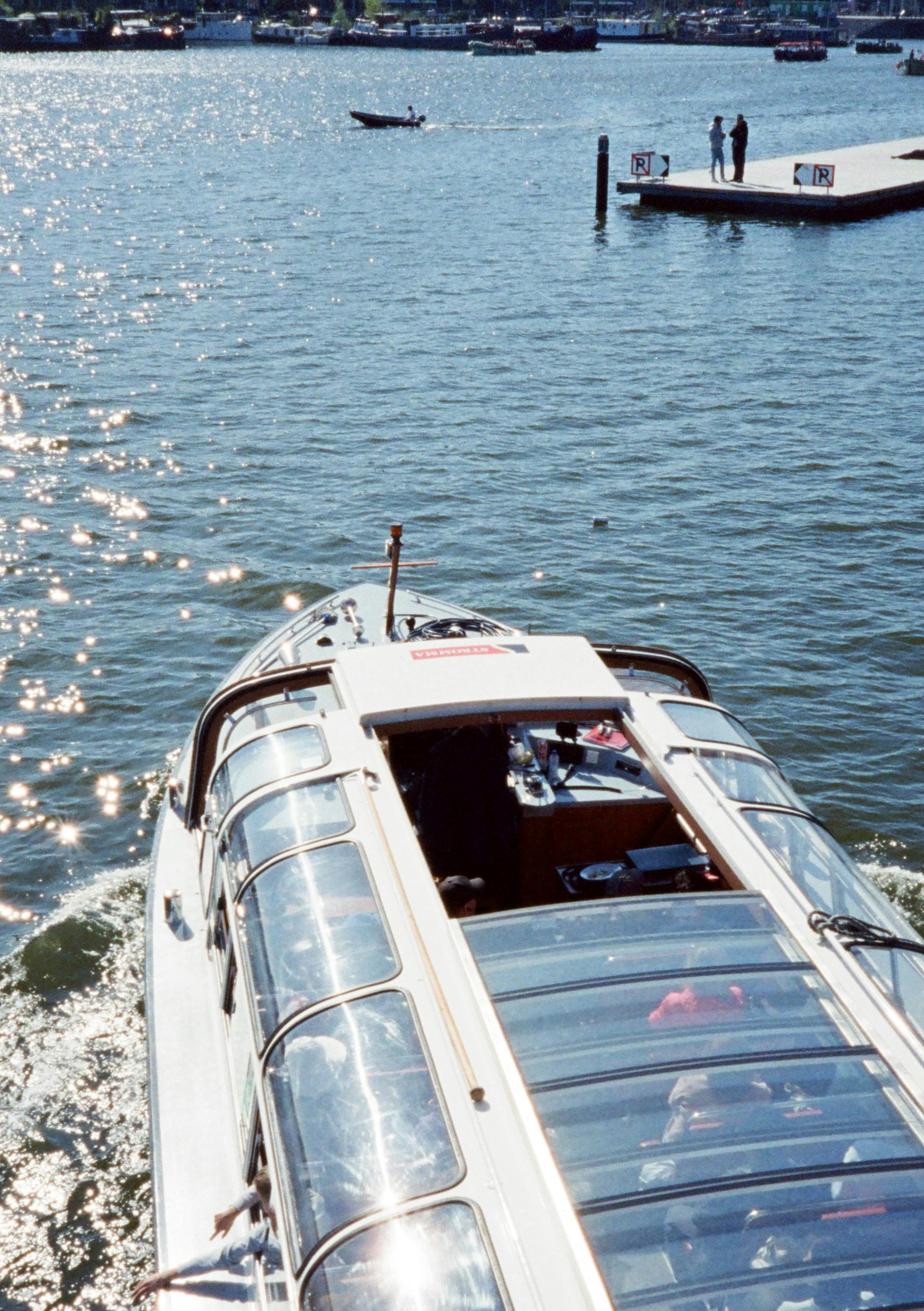 A glass-roofed tour boat cruises on sparkling water