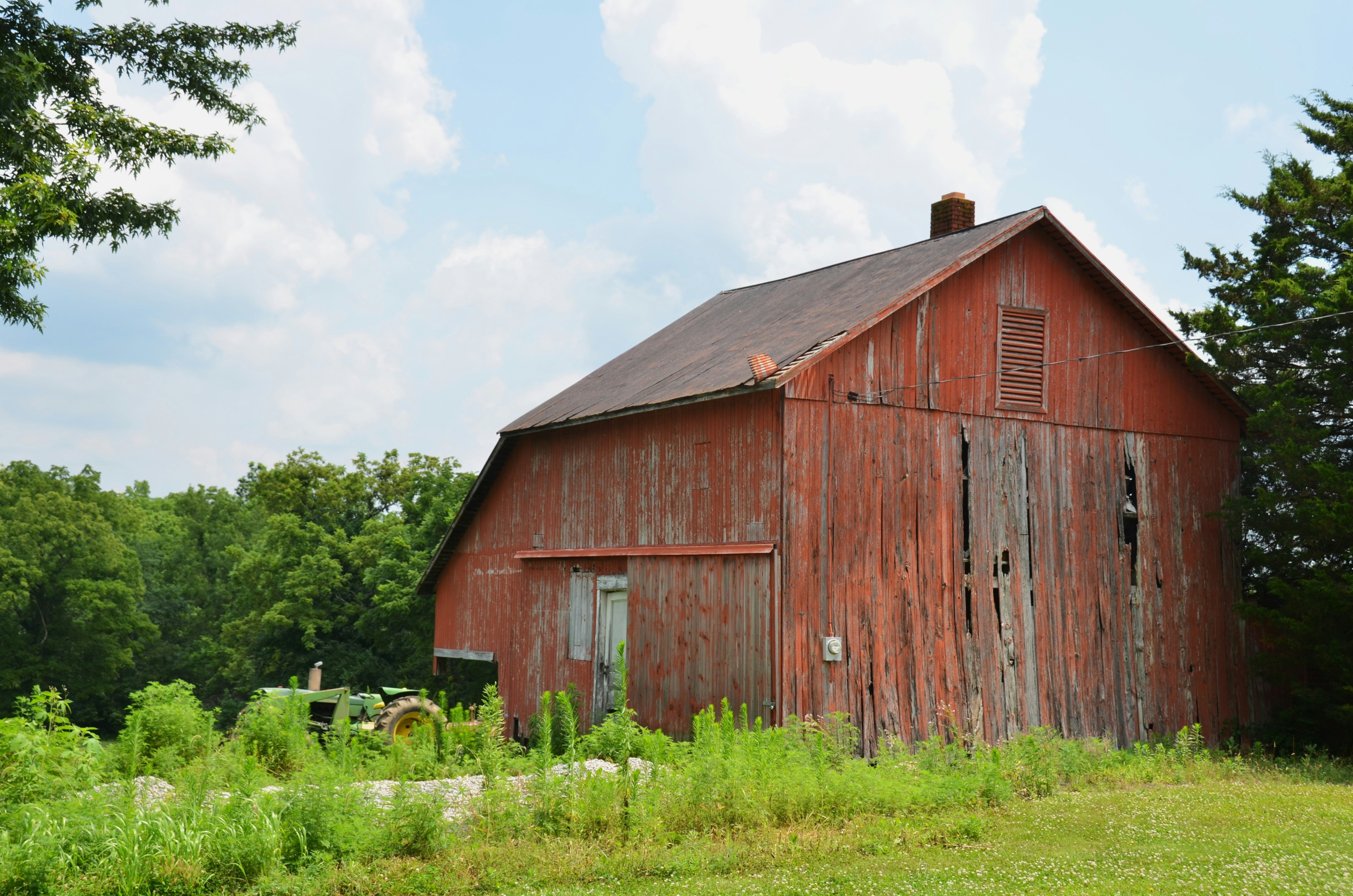 An old red barn in a green rural landscape.