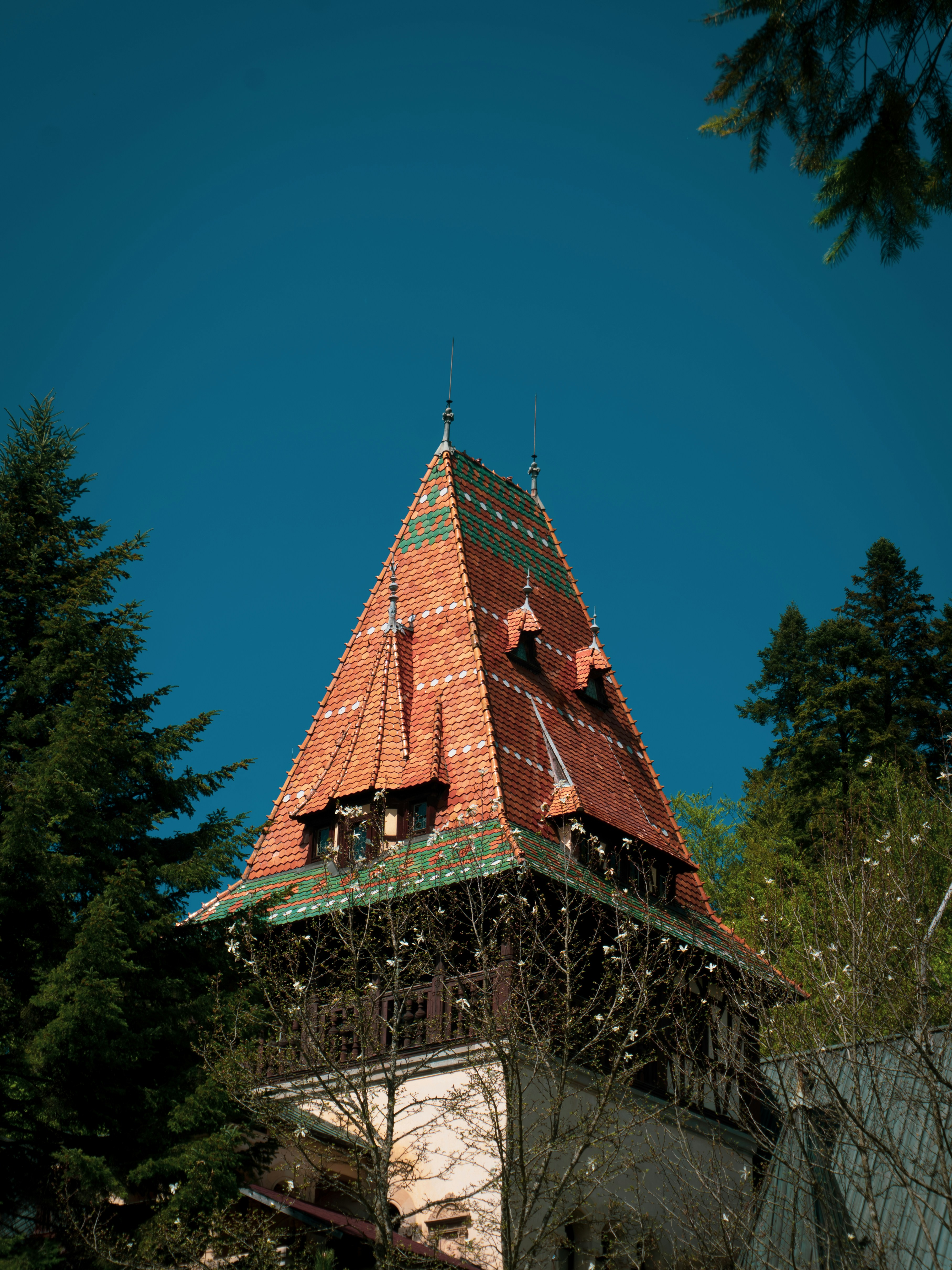 Old castle tower with colorful tiled roof against blue sky
