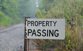 A "property passing" sign stands beside railroad tracks.