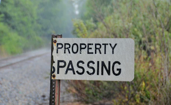 A "property passing" sign stands beside railroad tracks.