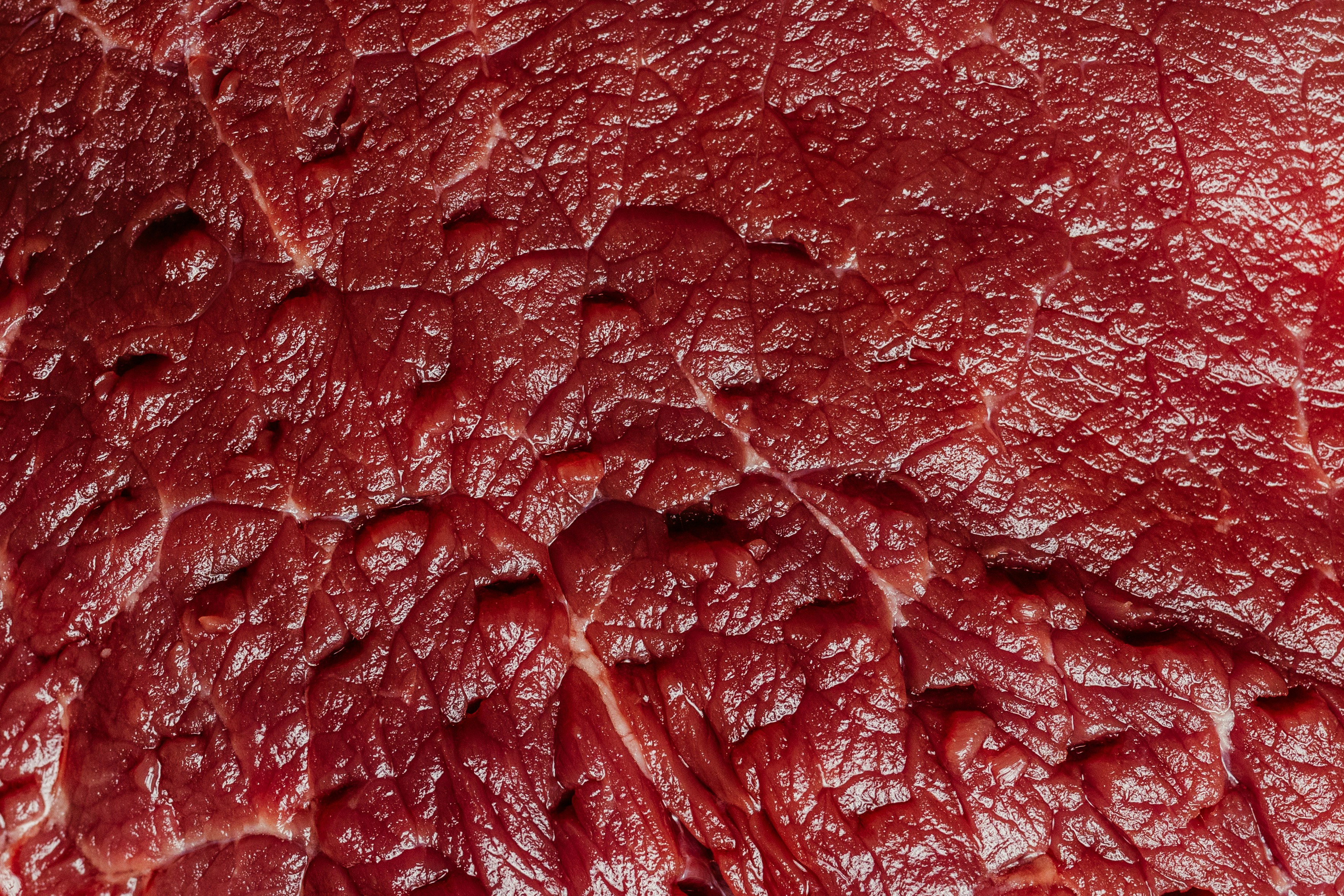 Close-up texture of raw red meat, showing fibers.