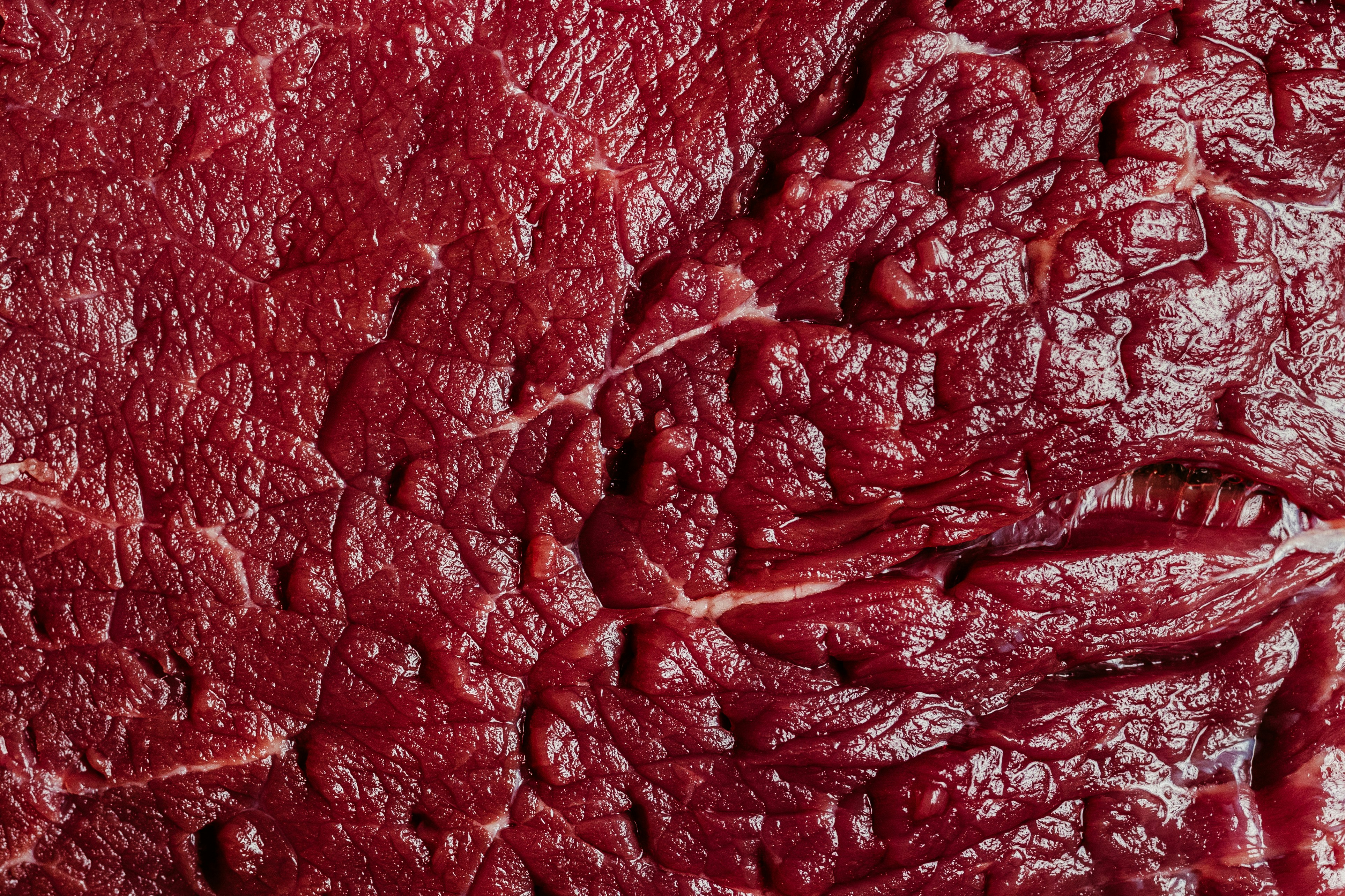 Close-up texture of raw red meat with visible fibers.