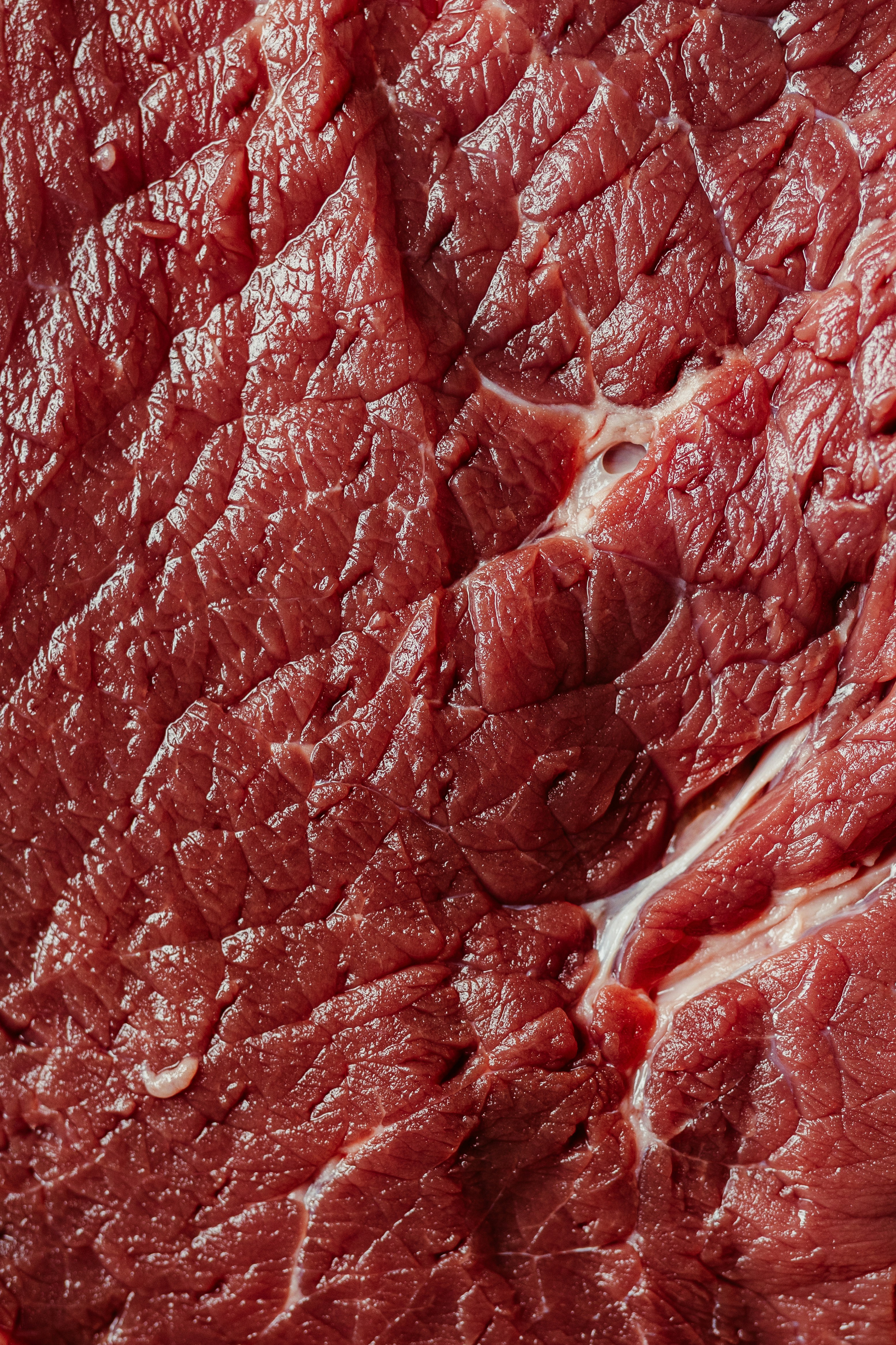 Raw red meat with visible muscle fibers and texture.