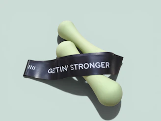 Light green dumbbells wrapped with a "gettin' stronger" resistance band