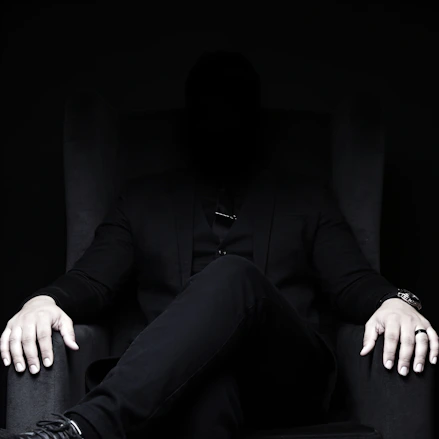 Mysterious man in dark suit sits in a chair