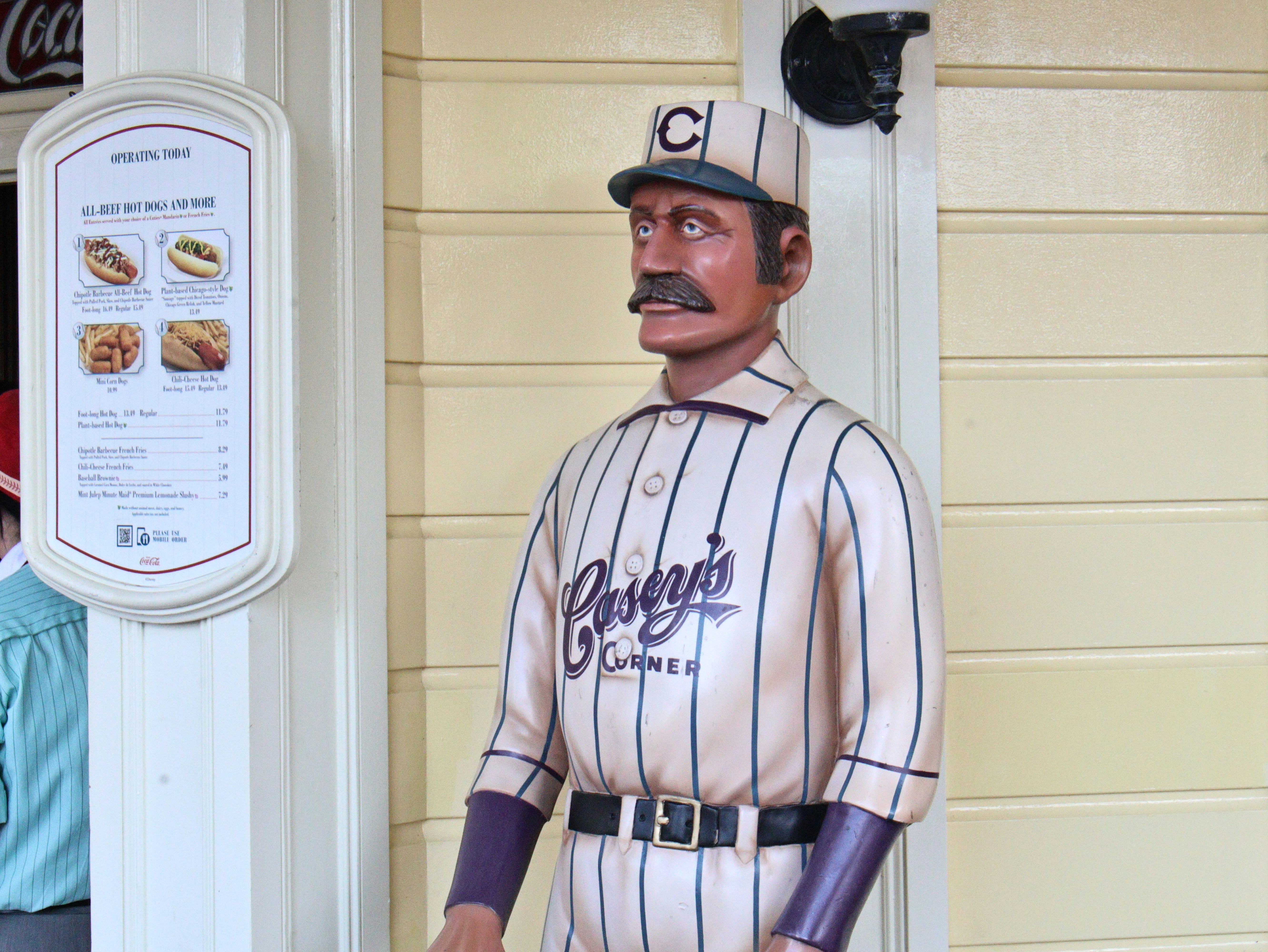 A baseball player statue with a cigar and menu board.