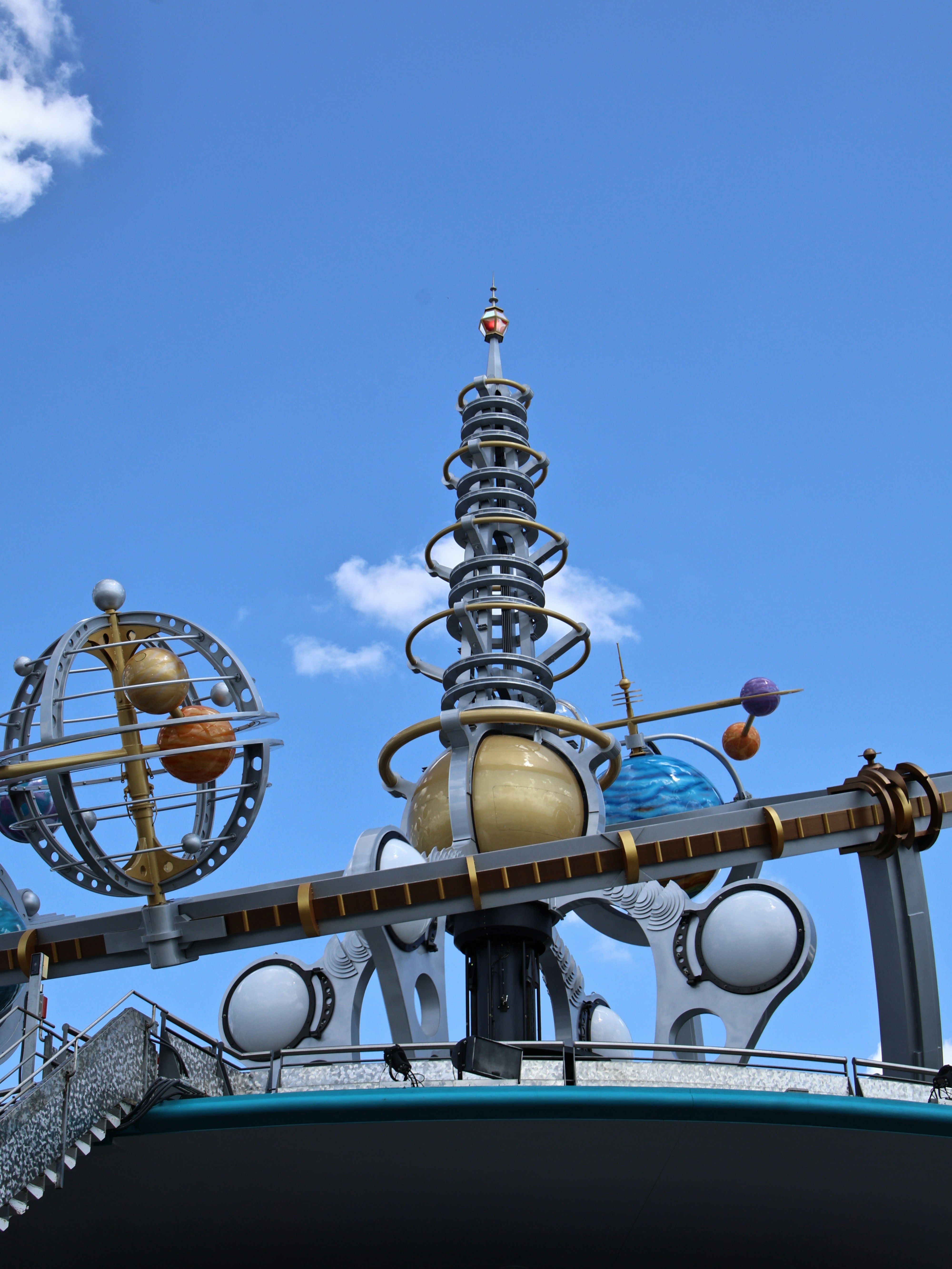 A futuristic space-themed structure with planets against a blue sky.