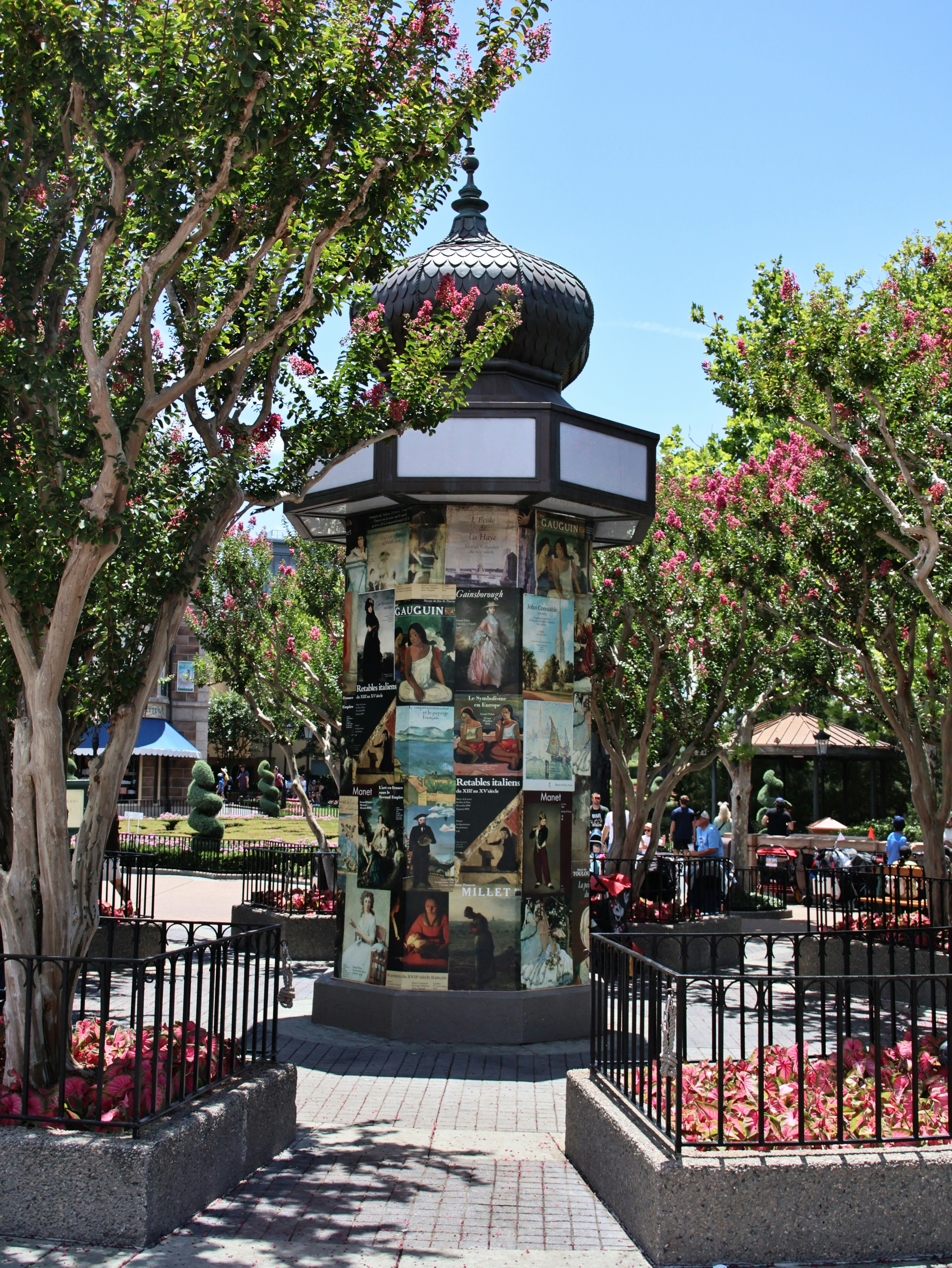 A tall, decorative kiosk surrounded by trees with pink flowers.