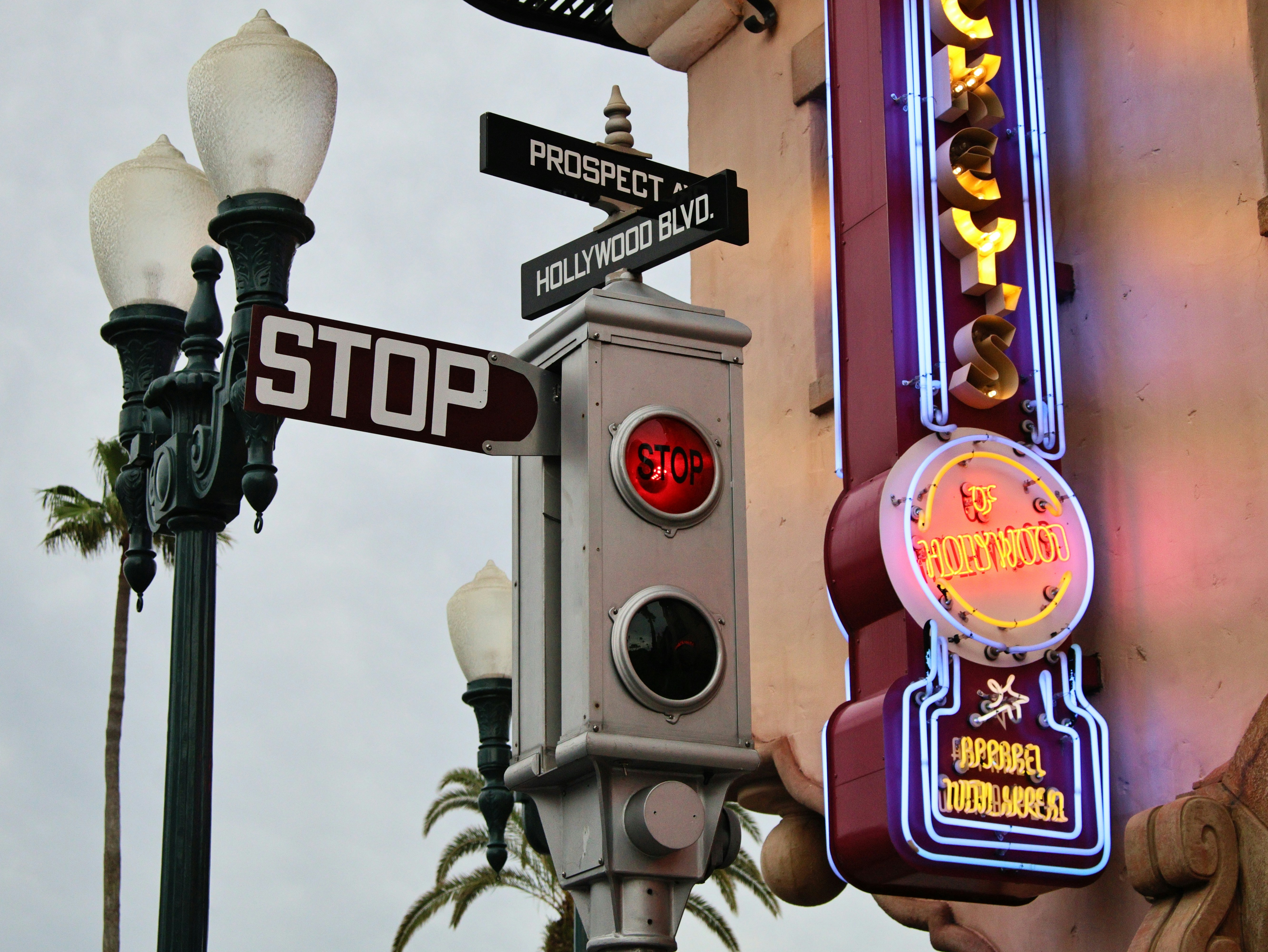 Street signs, a red traffic light, and a neon sign.