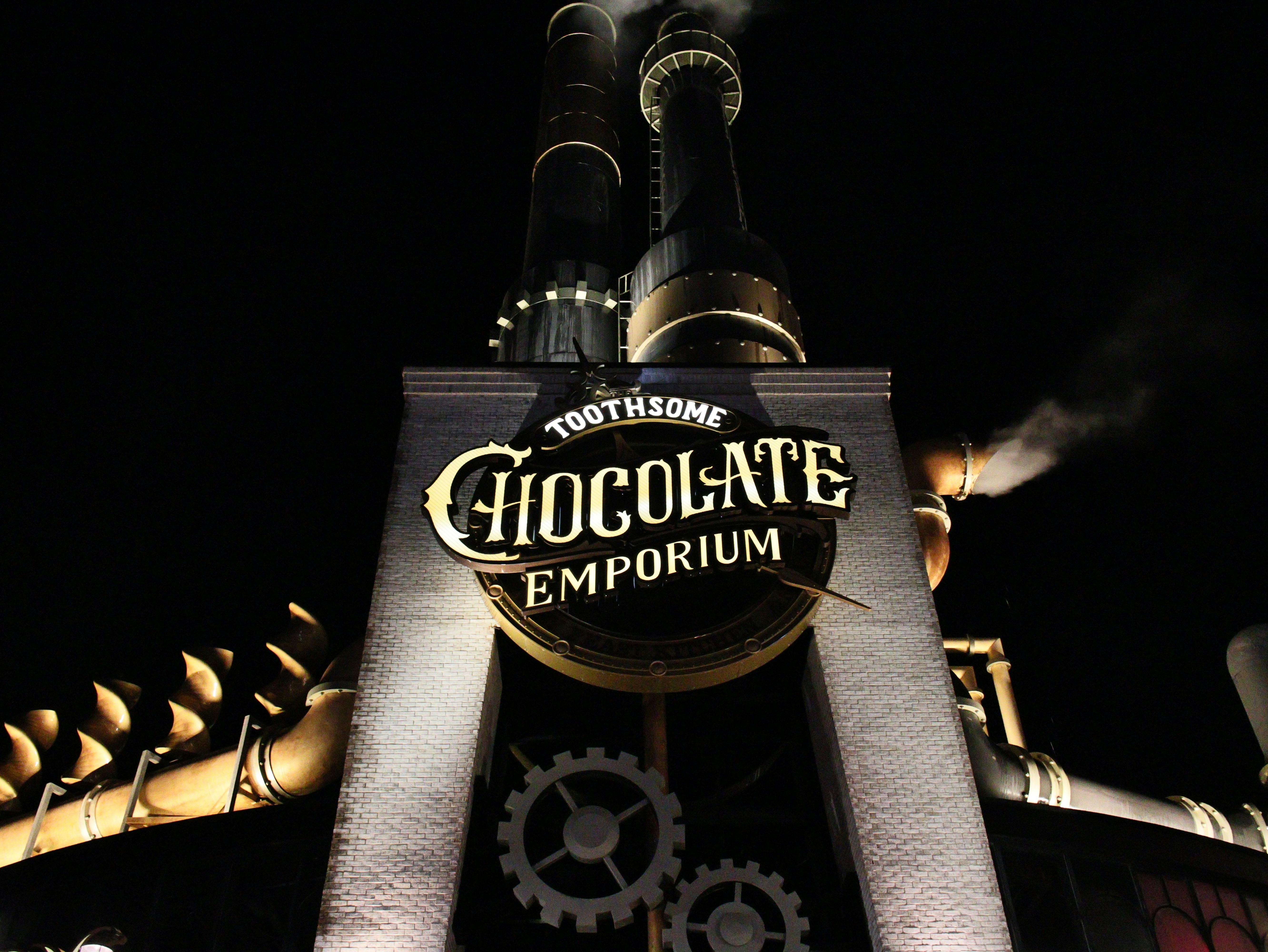 Toothsome chocolate emporium building with smokestacks at night.
