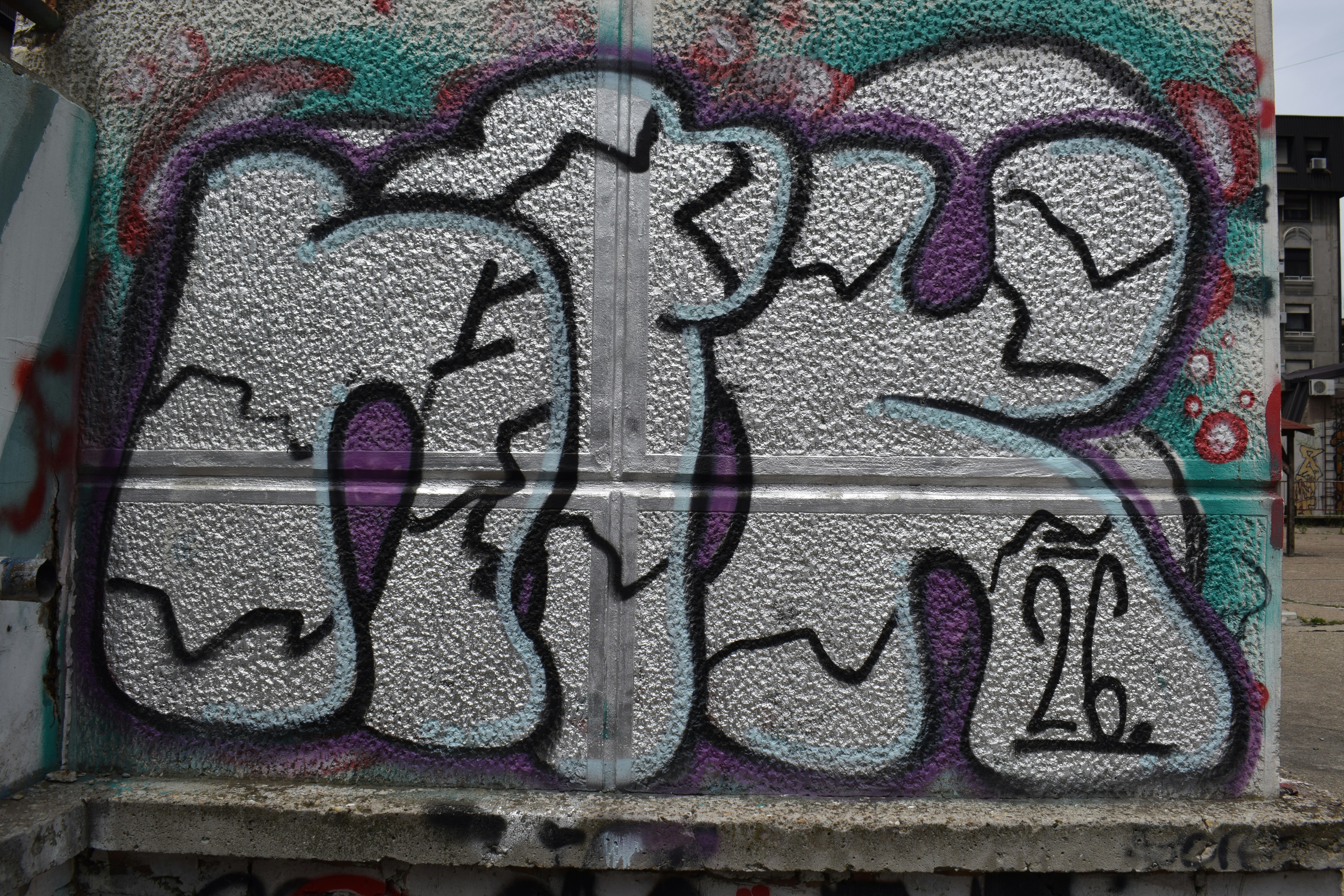 White and purple bubble graffiti on a concrete wall.