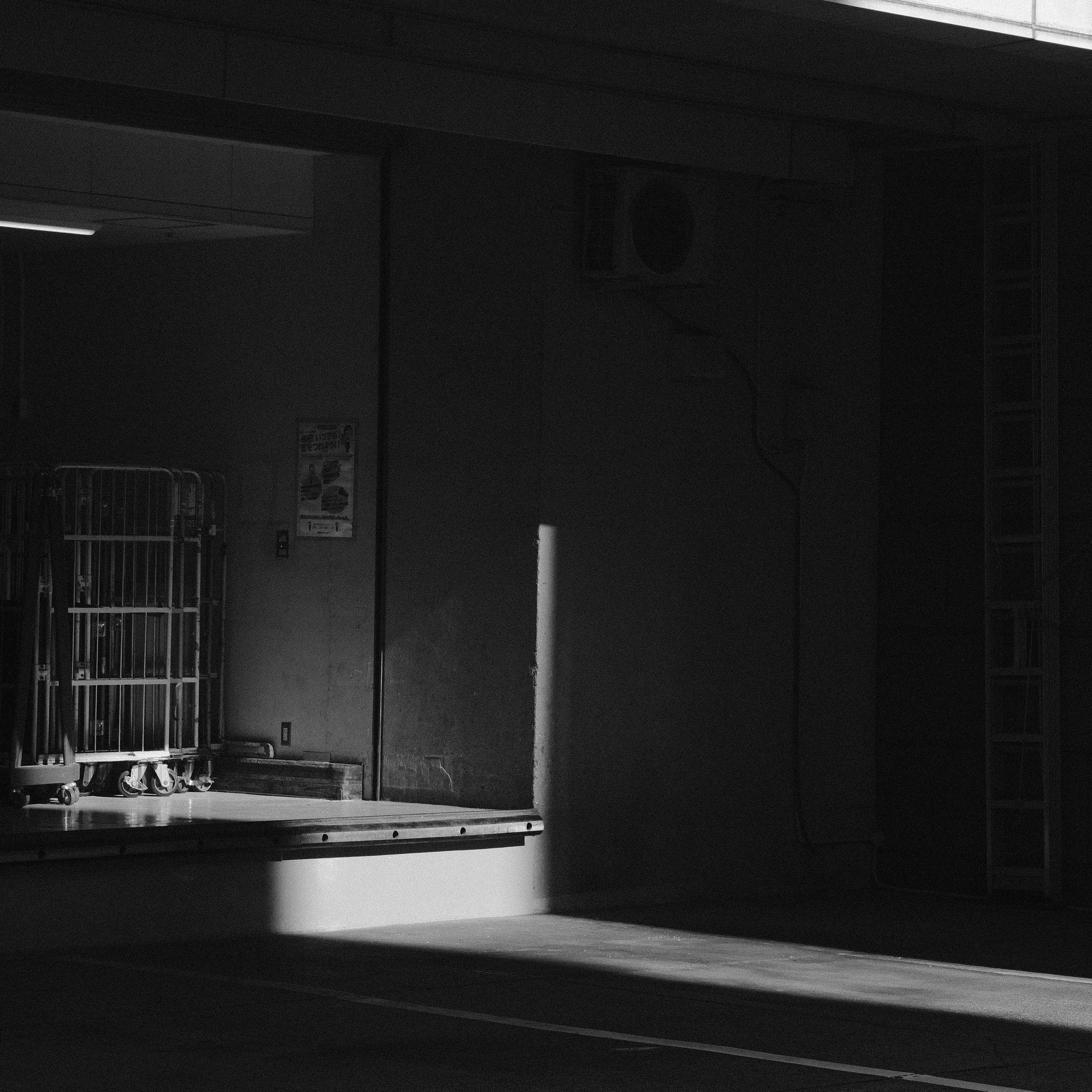 A luz forte do sol entra em um prédio industrial escuro e vazio.
