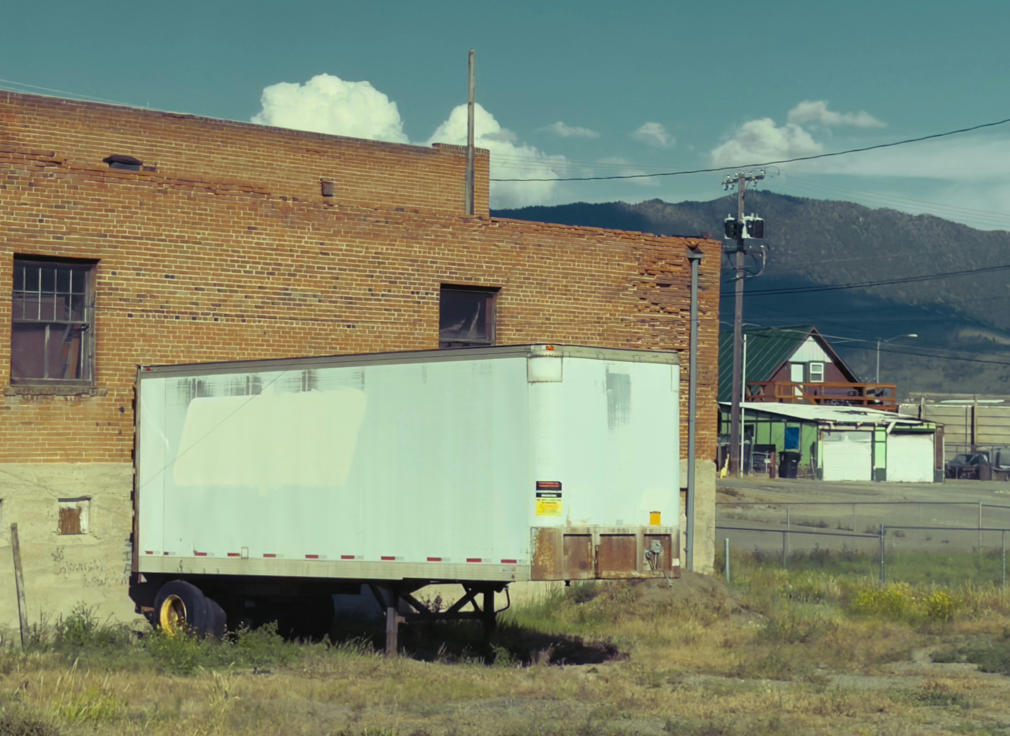 A white trailer parked beside an old brick building.