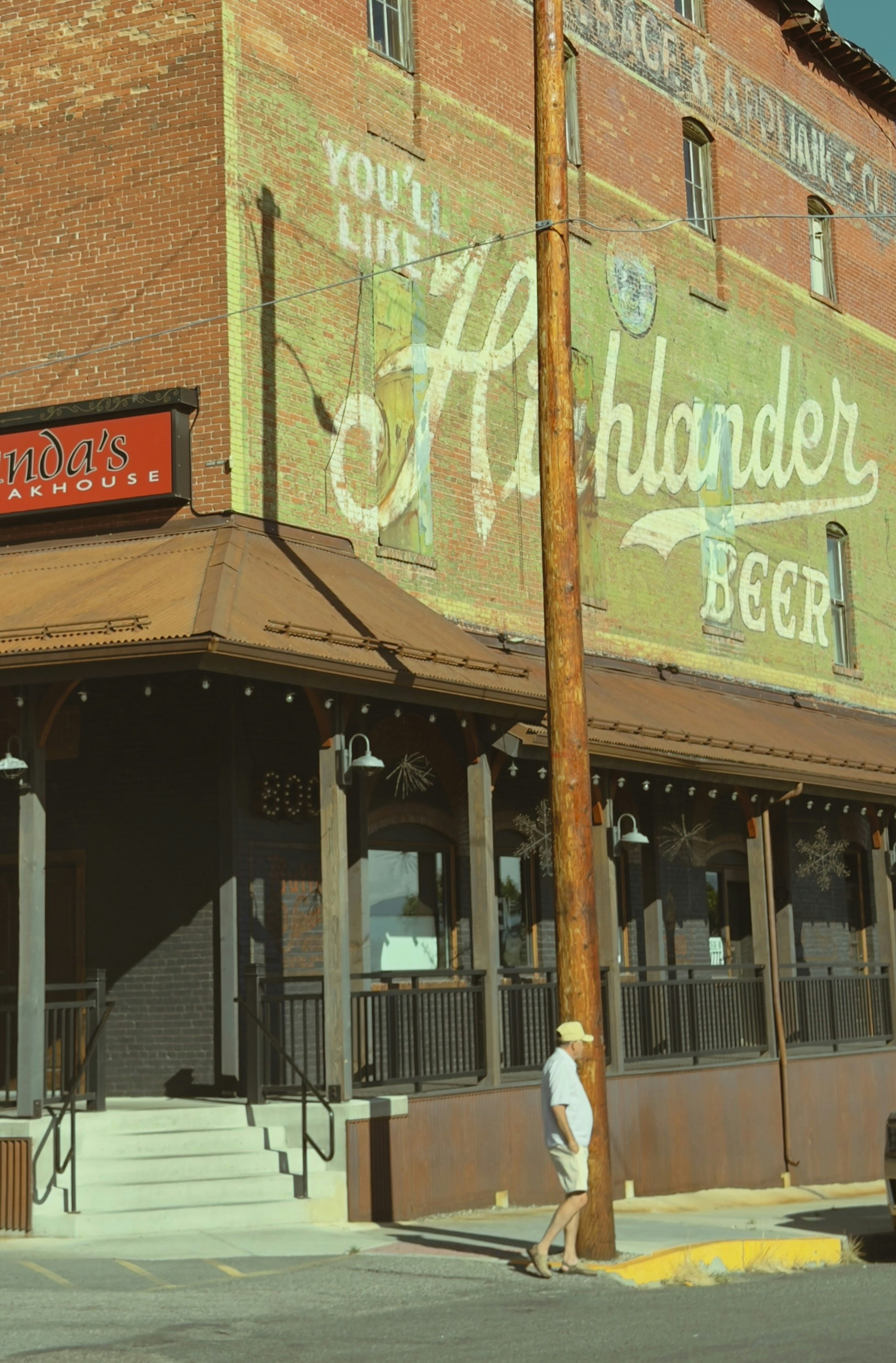 Old brick building with highlander beer advertisement and a person.