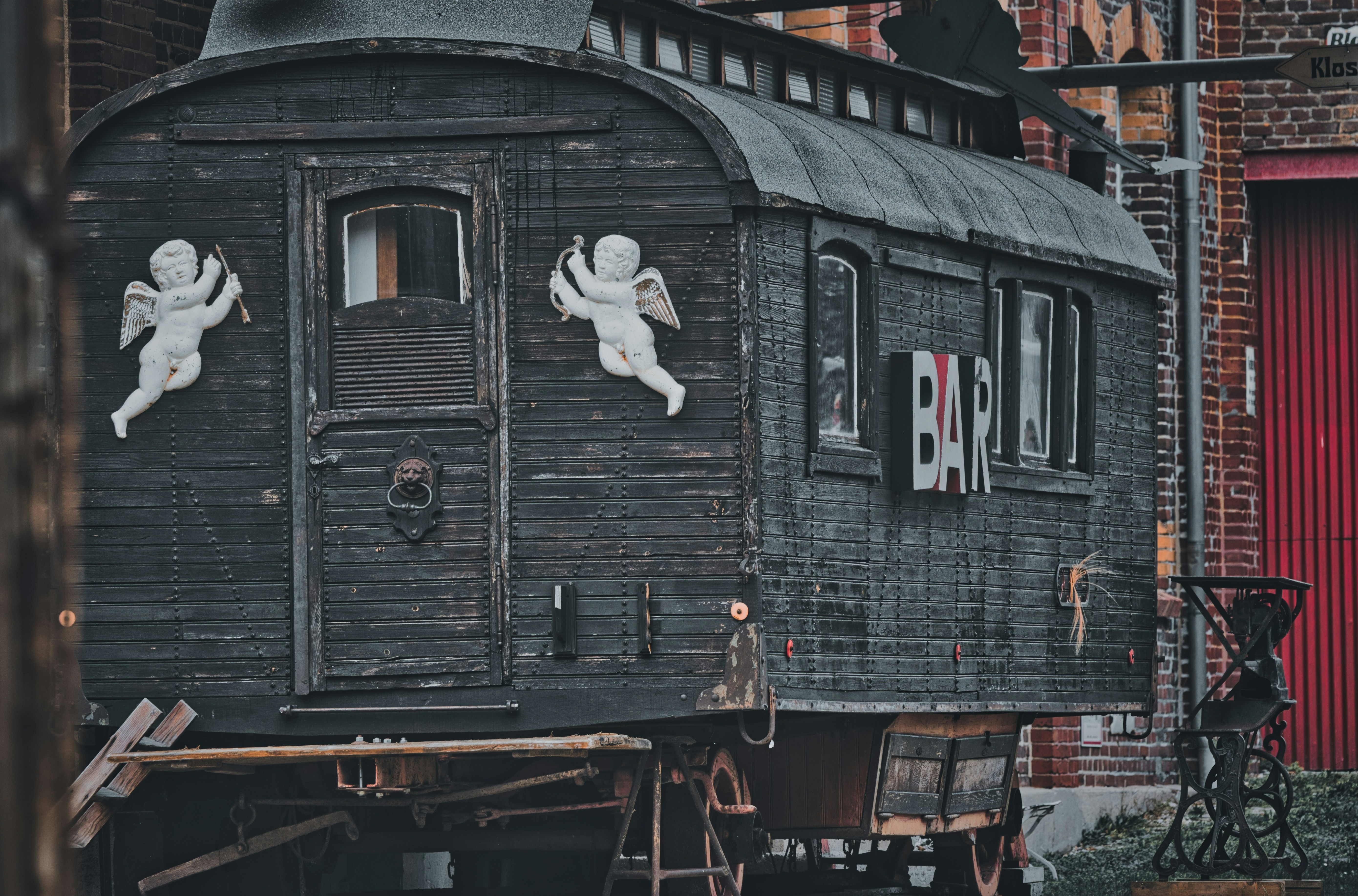 An old, dark wooden bar wagon with cherub decorations.