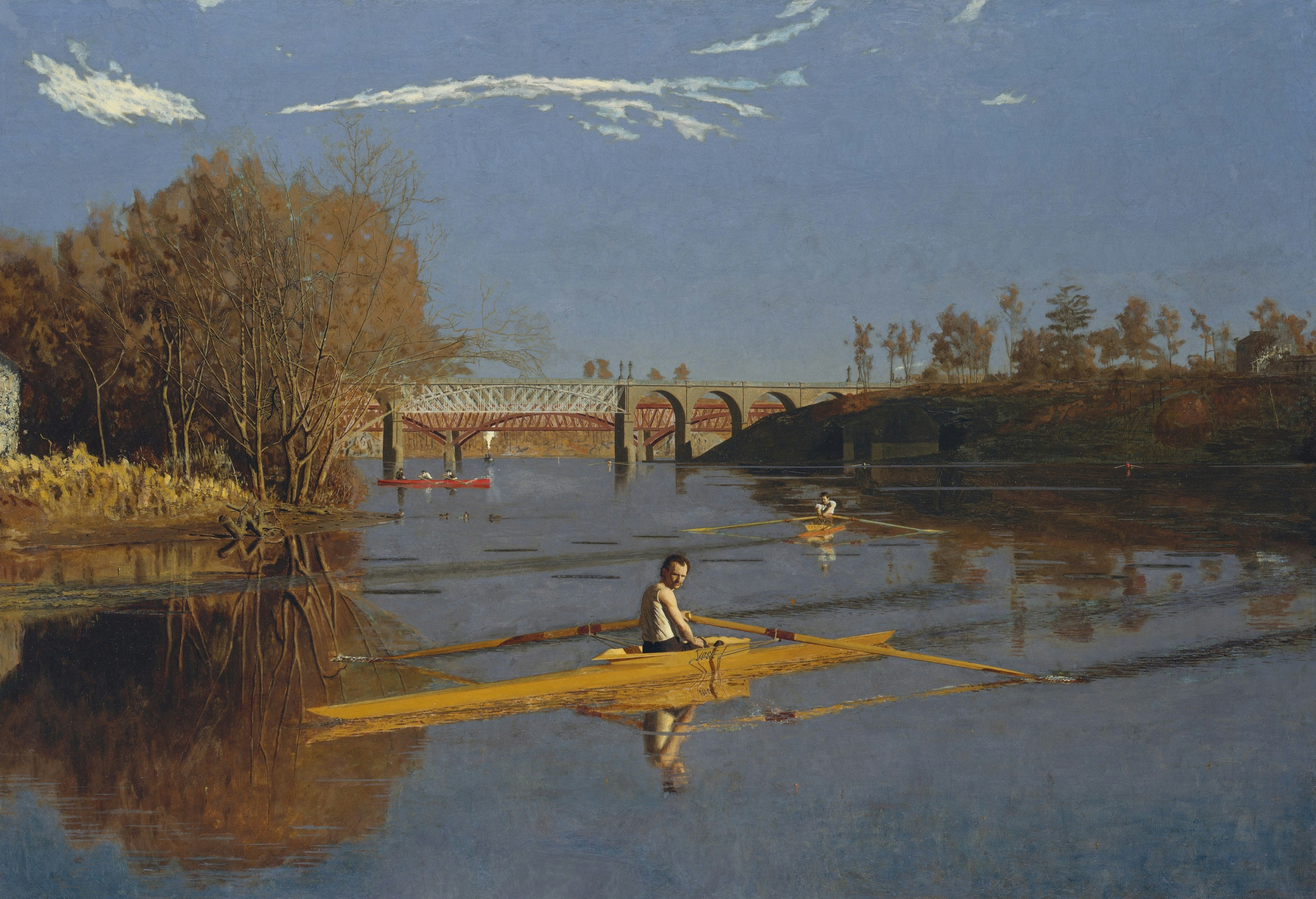 A lone sculler glides on a river under a bridge
