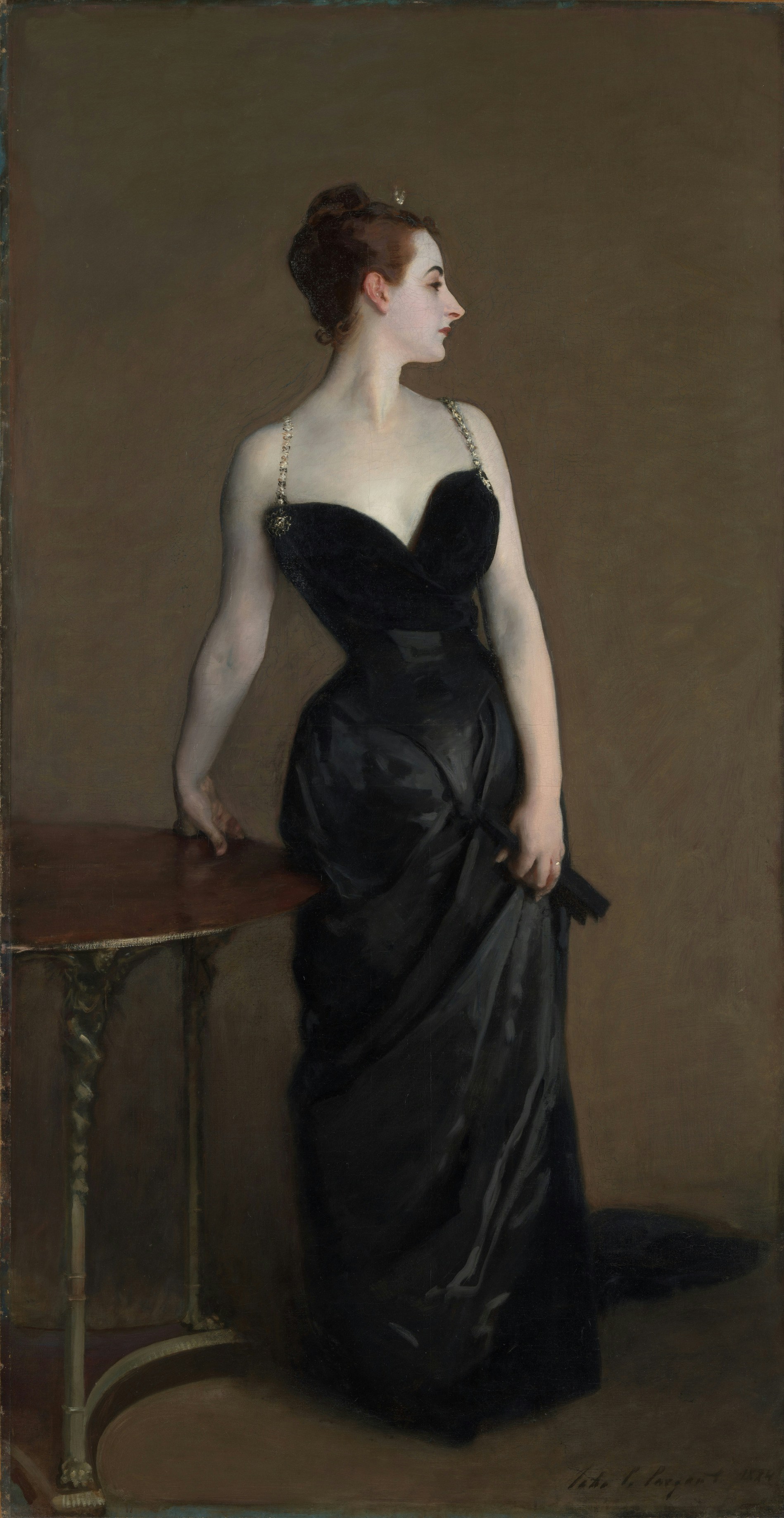 Elegant woman in black gown standing beside a table