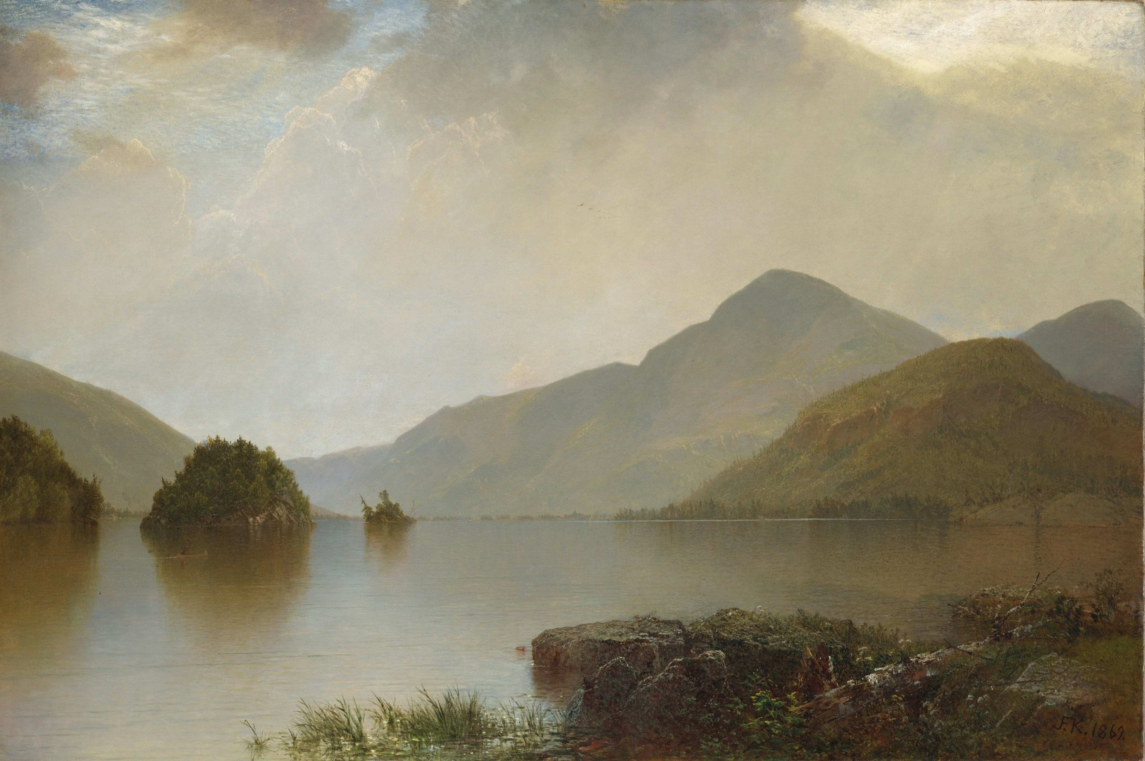 A serene lake surrounded by mountains under a cloudy sky