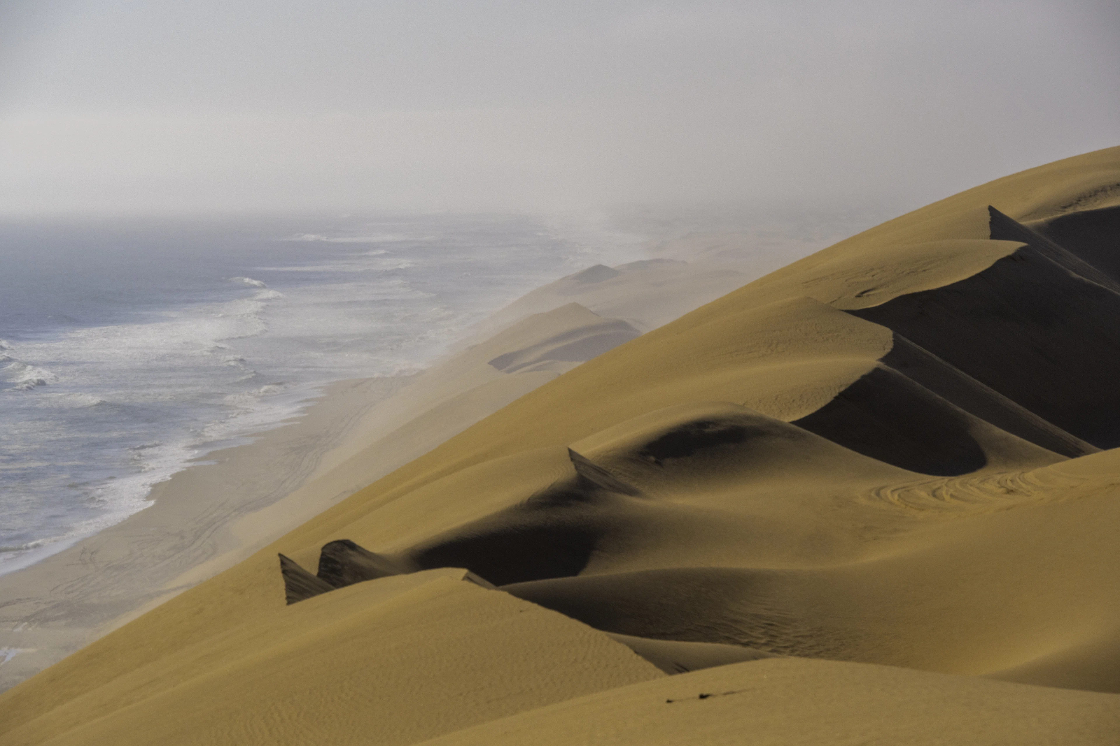 Namib dunes running straight down into the Atlantic on a hazy day