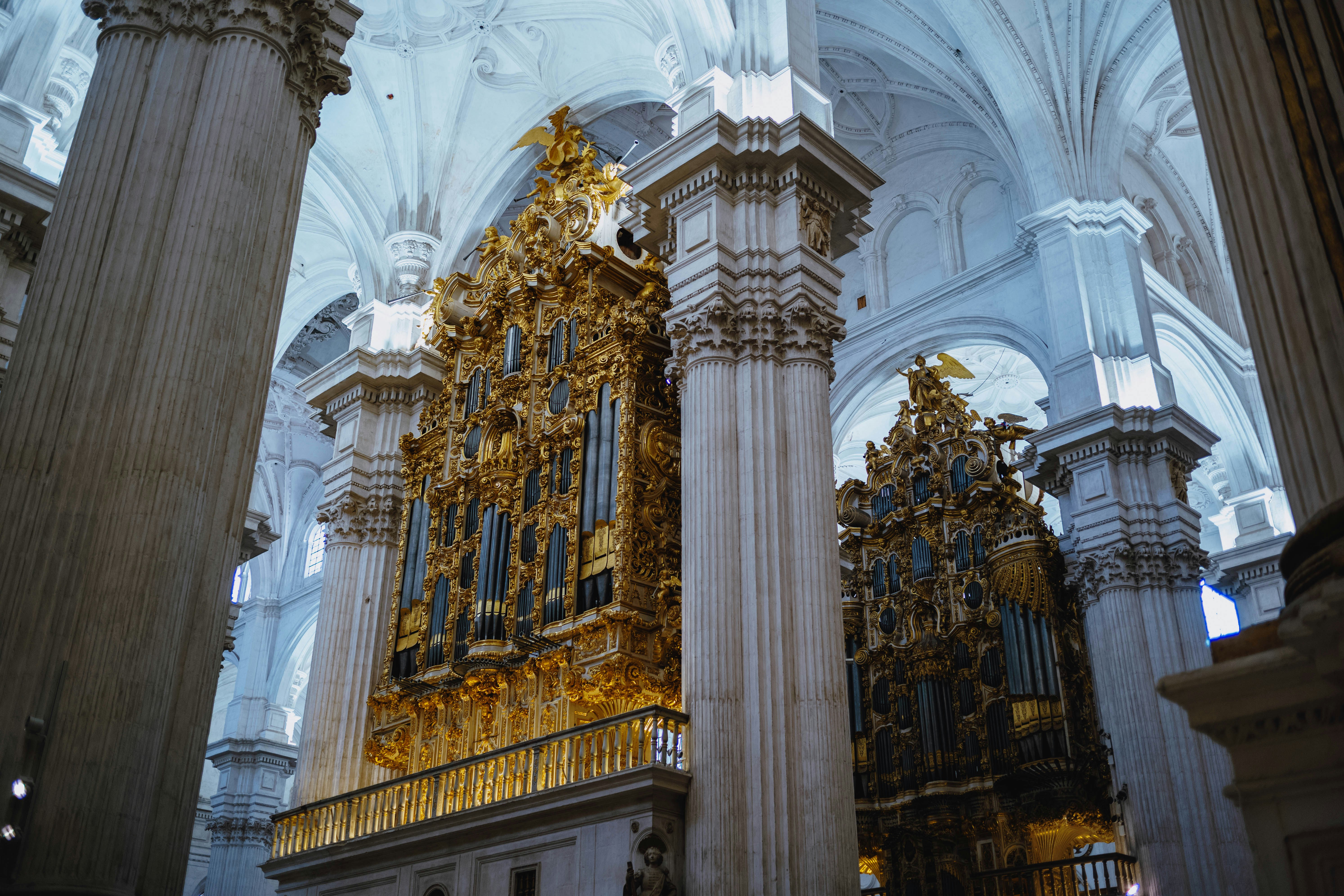 Organo dorato ornato all'interno di una grande cattedrale con alte colonne.