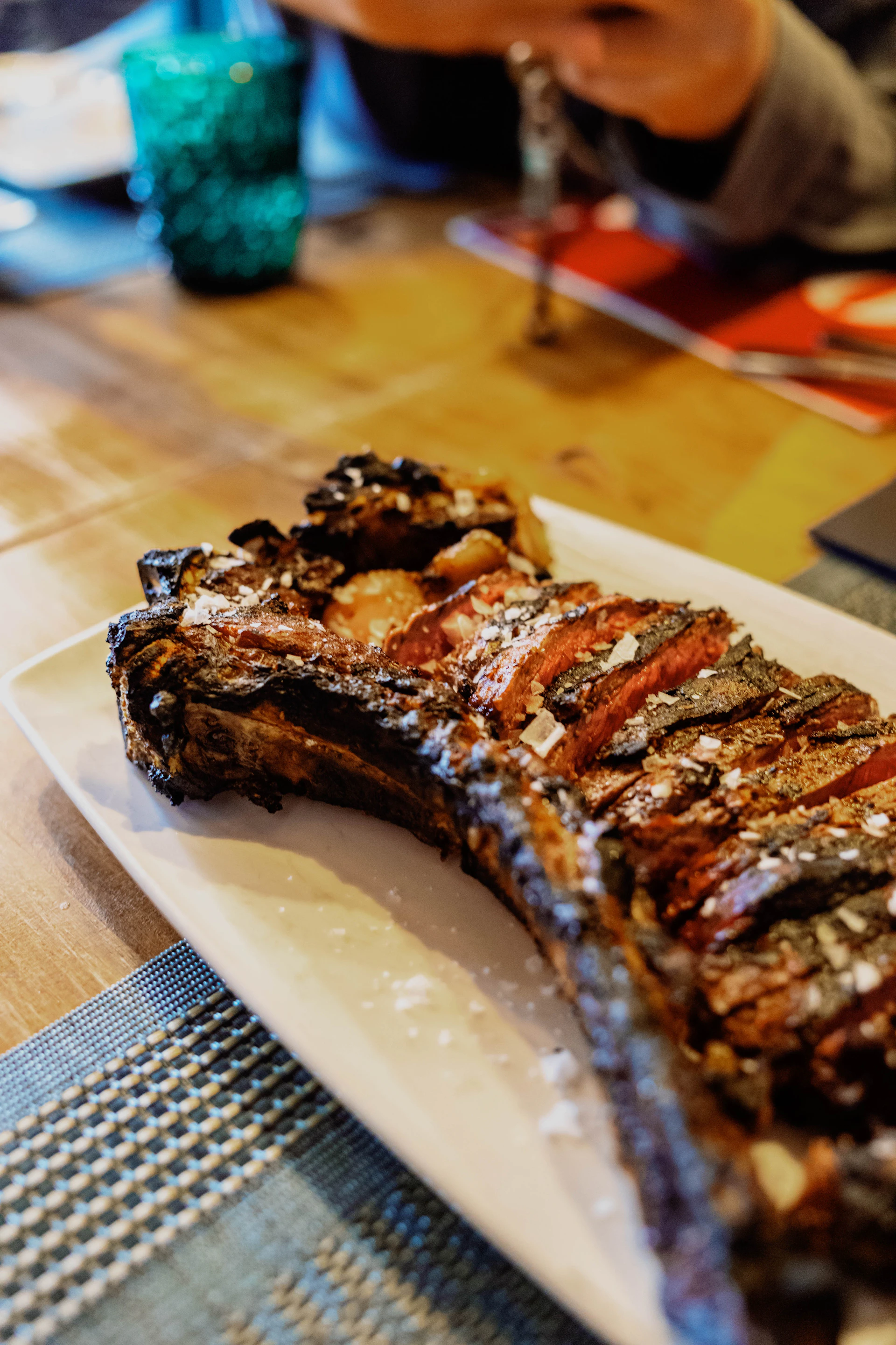 Large grilled steak, sliced and seasoned, on a white plate