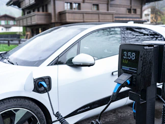 White electric car charging at a station.