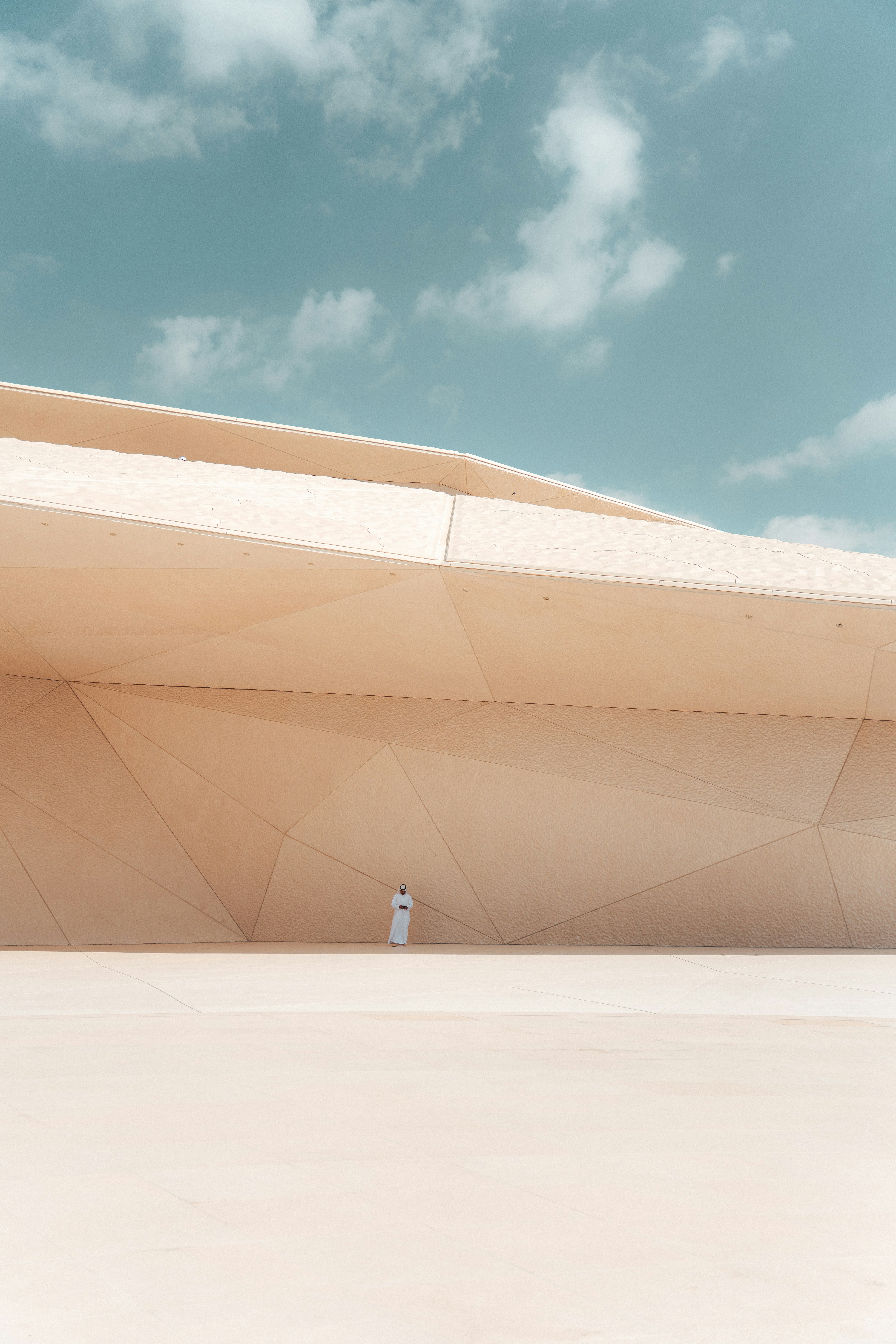 A person stands before a modern, geometric building.