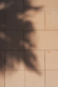 Abstract shadows of leaves on a light beige tiled wall