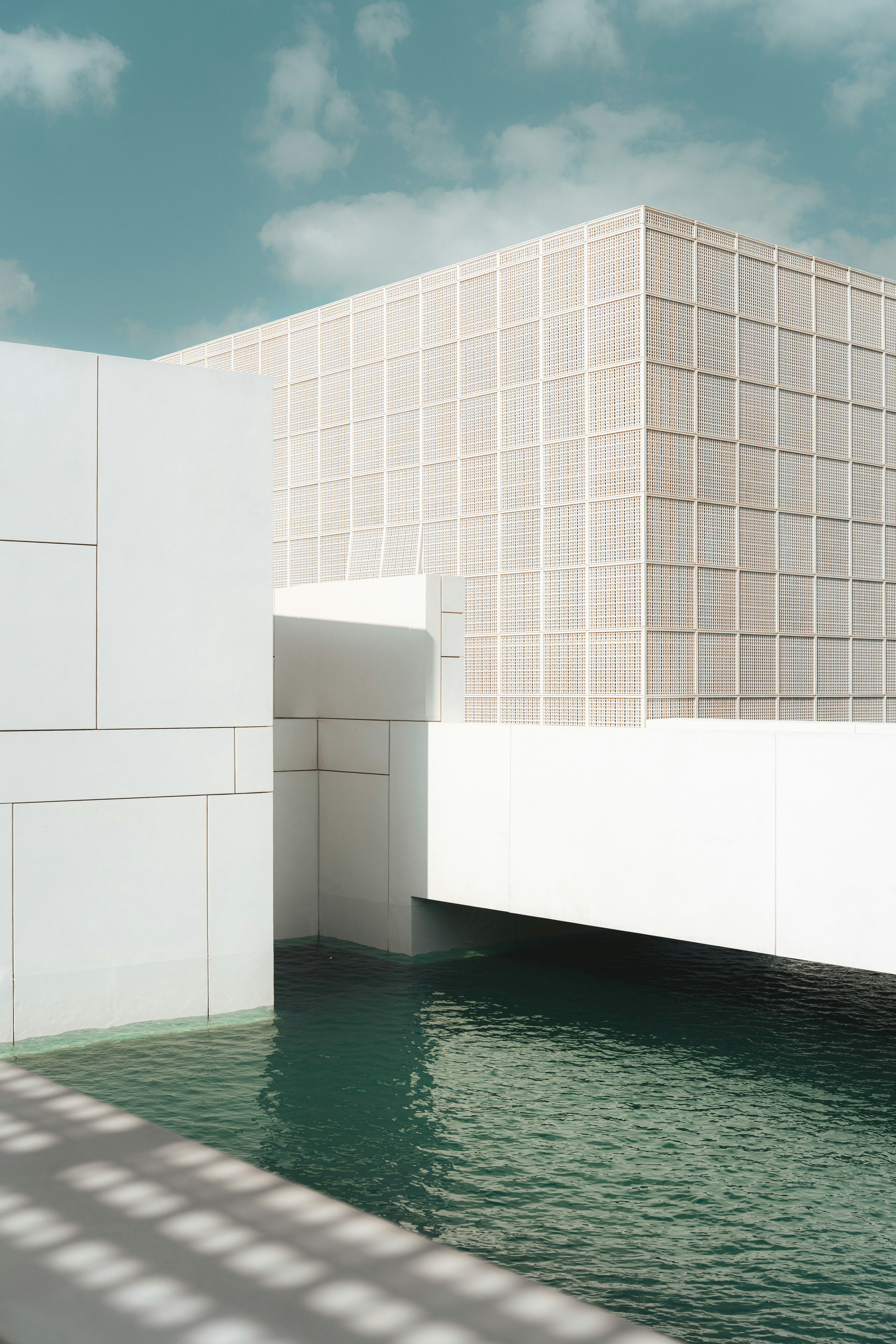 Modern white buildings with water under a blue sky.