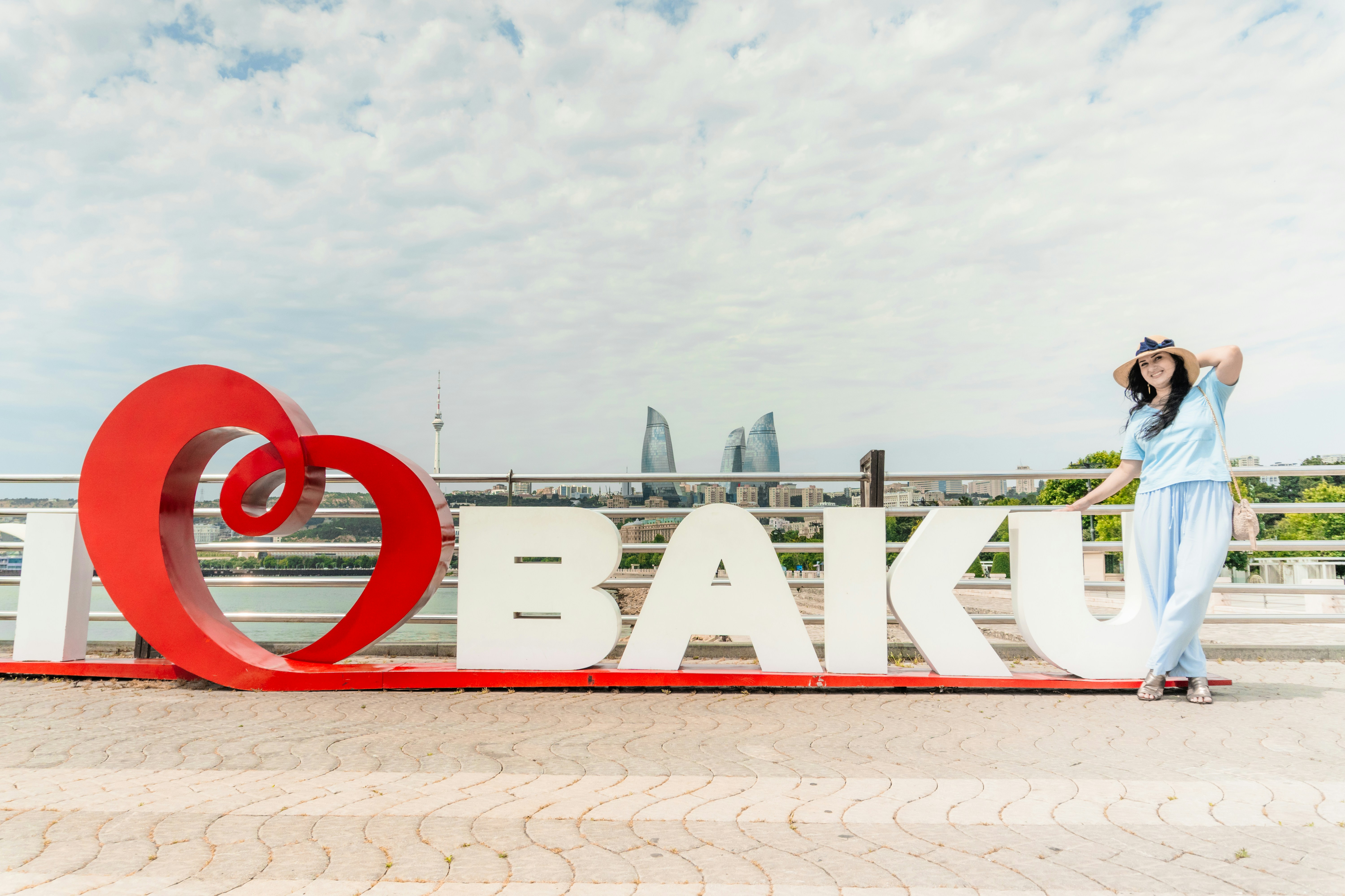 "I love baku" 표지판과 스카이라인을 들고 포즈를 취한 젊은 여성.