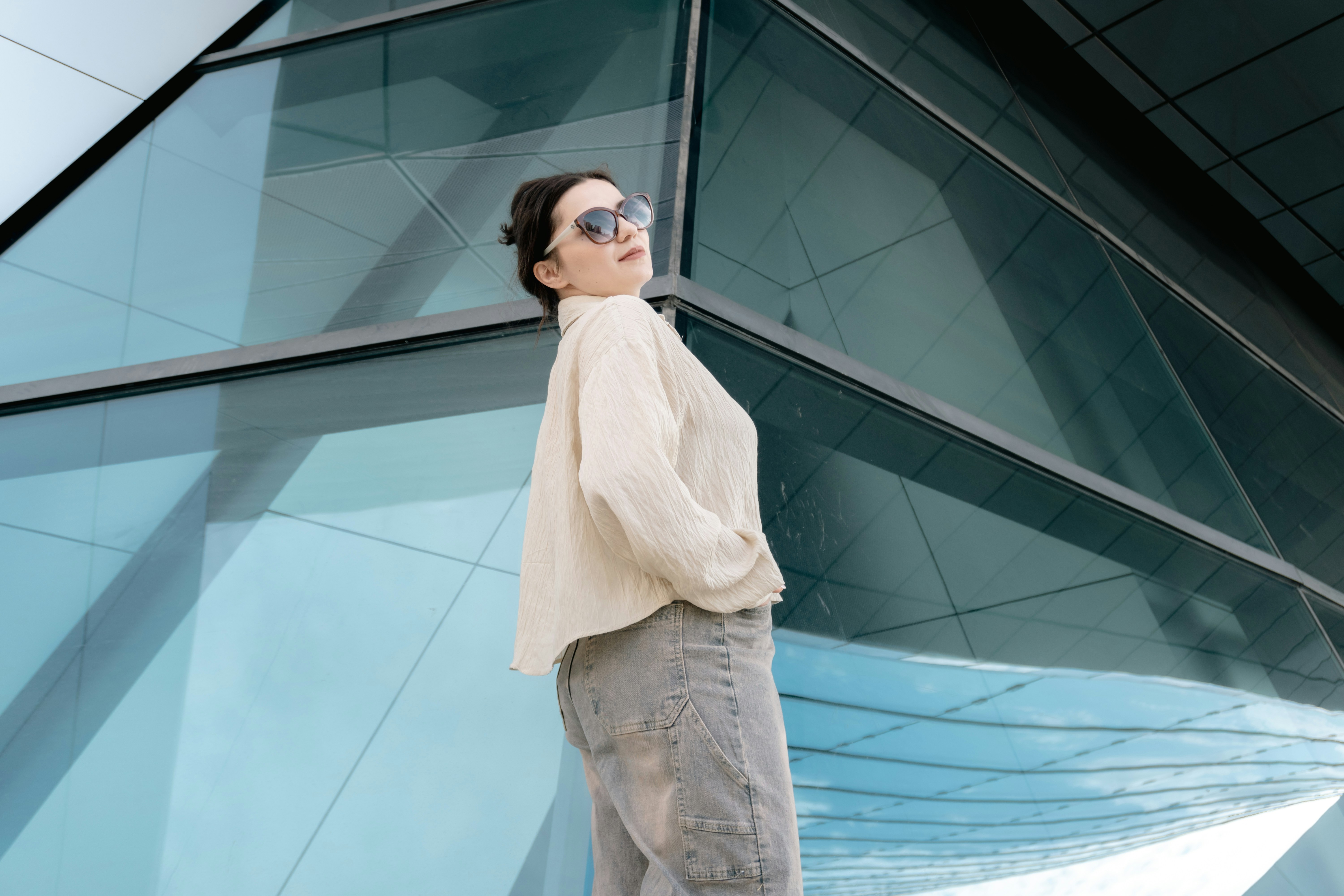 Stylish woman poses against a contemporary glass building facade.